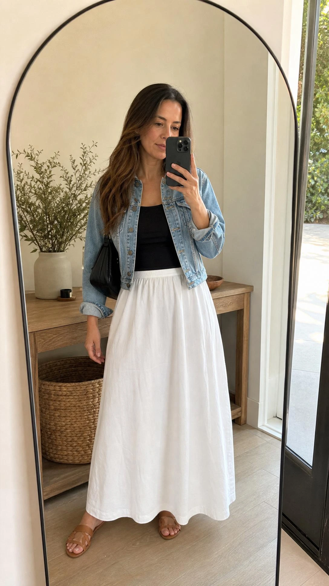 Mirror selfie of a white maxi skirt outfit with a light denim jacket, fitted black bodysuit, and softly draped cotton skirt