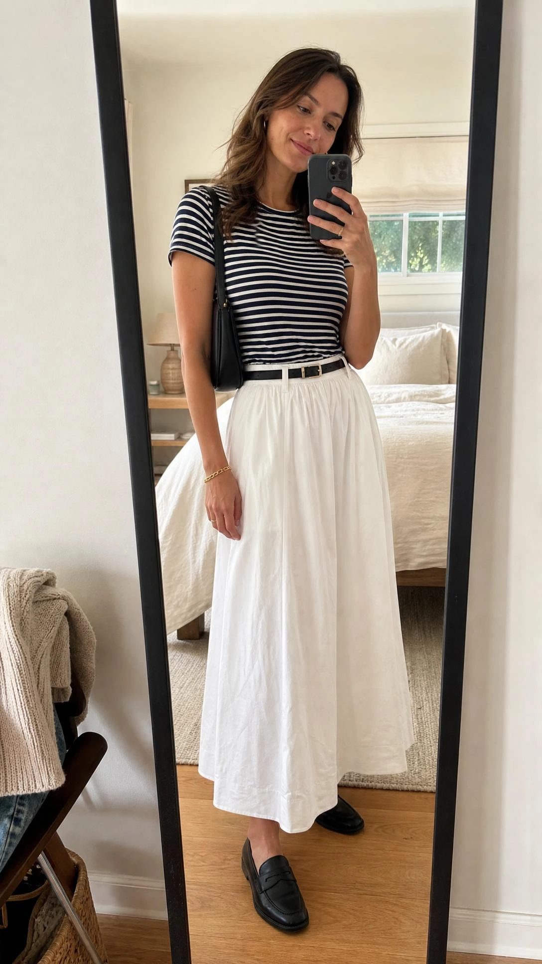 Woman in a striped tee and black loafers poses in a bedroom mirror for white maxi skirt outfit ideas