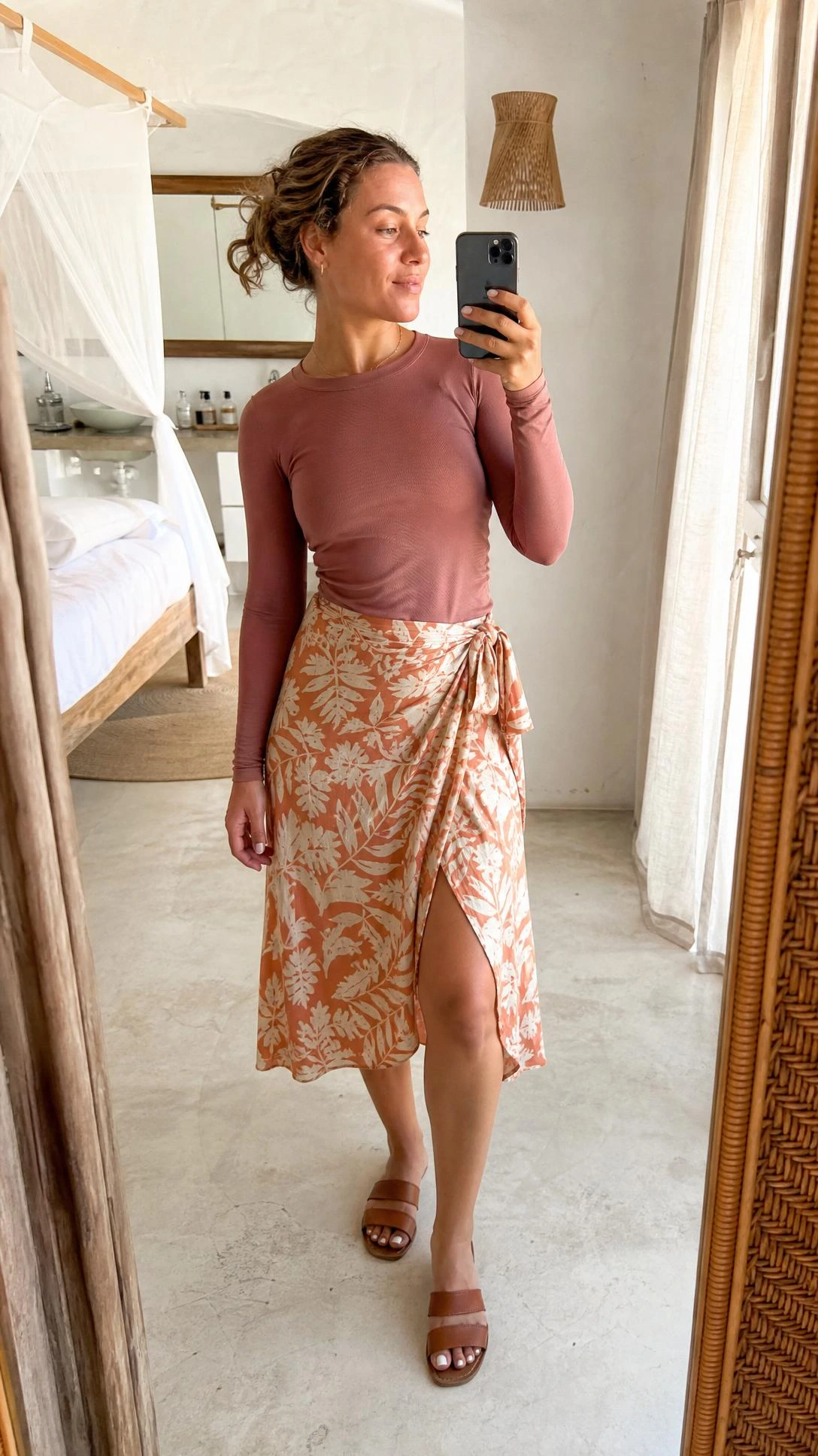 Woman in dusty rose long-sleeve rashguard and terracotta botanical wrap midi skirt showing a modest beach outfit that balances sun protection with effortless coastal style