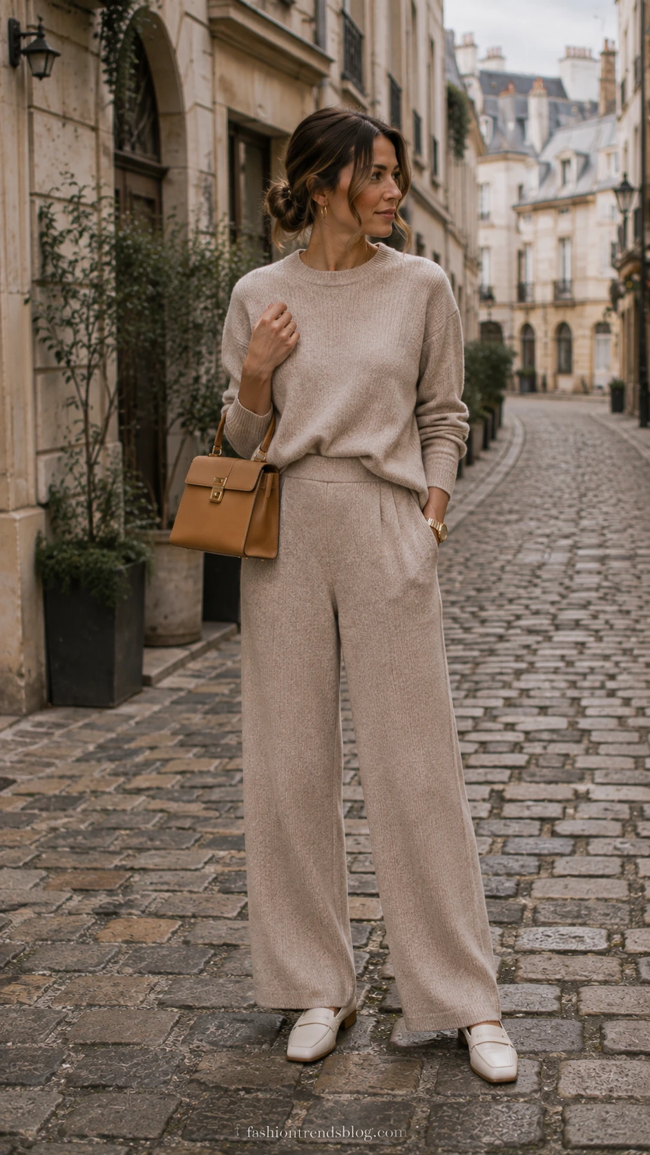 Teacher wearing a monochrome oatmeal beige ribbed knit sweater and matching bottoms on a cobblestone street, a polished casual Friday outfit idea