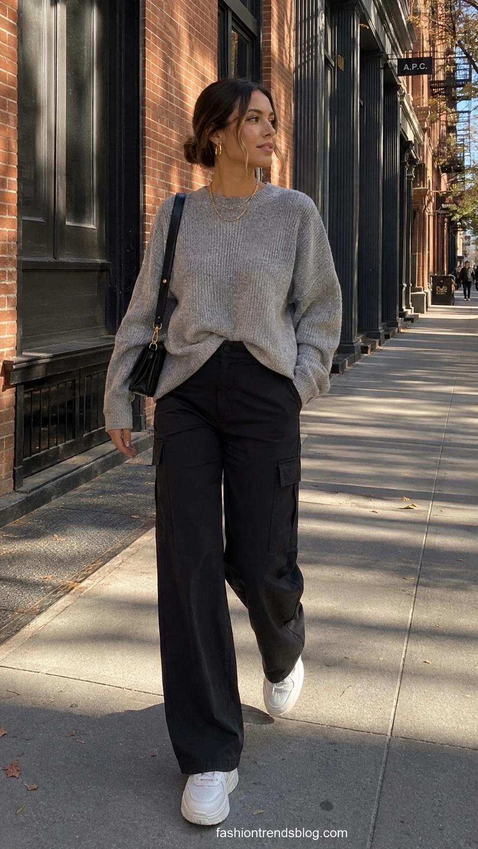 Woman wearing oversized heather-grey ribbed sweatshirt tucked into wide-leg black cargo pants, showcasing an effortless elevated streetwear outfit