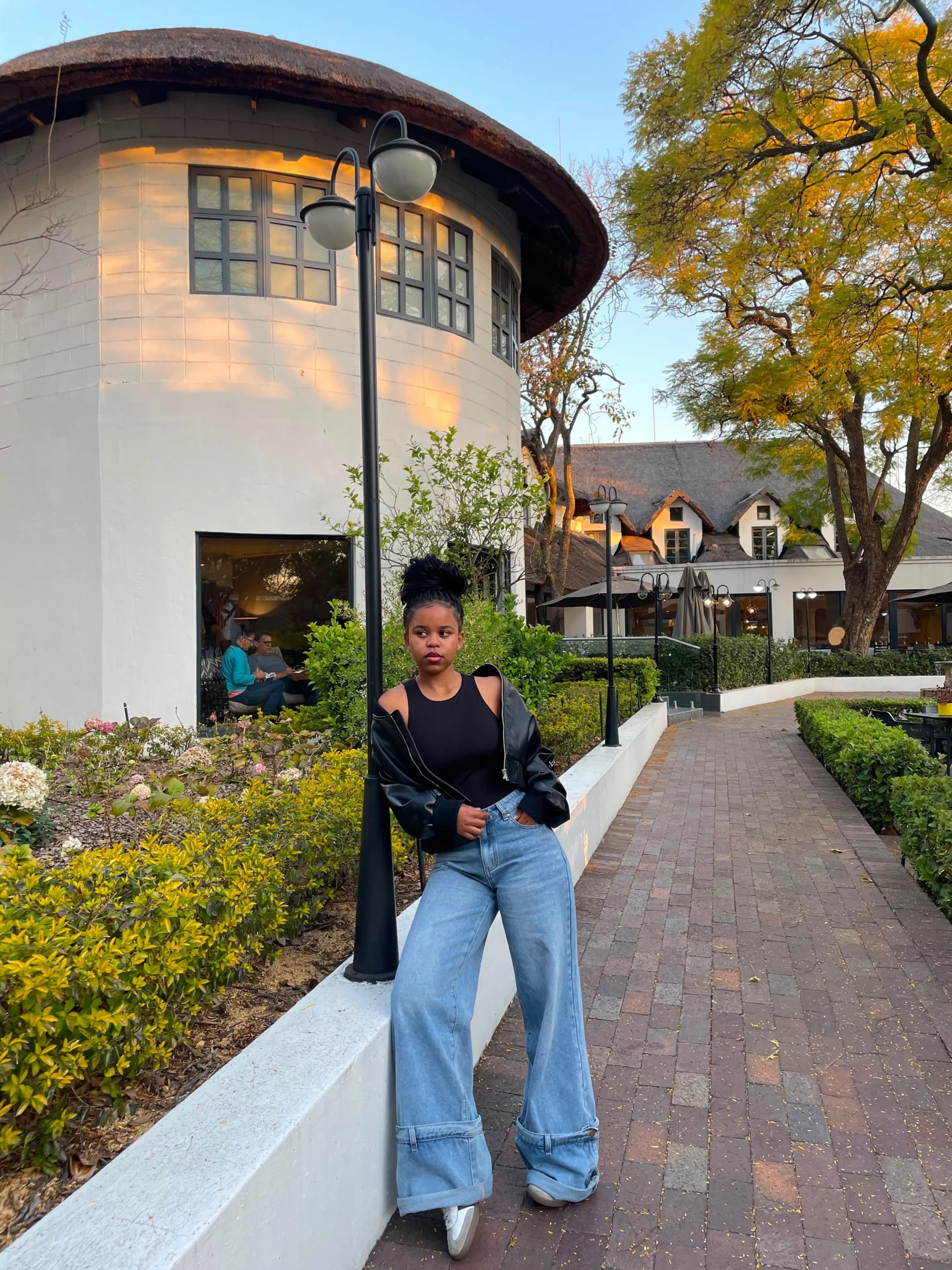 Black bomber jacket, wide-leg light-wash jeans, and white Adidas Samba sneakers styled together.