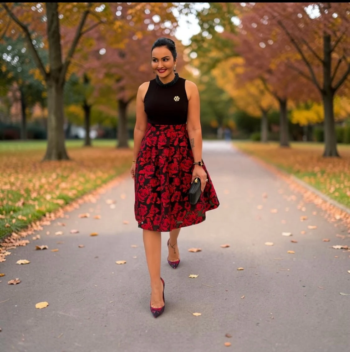 Sleeveless black top paired with a red floral flared skirt and pointed dark red shoes.