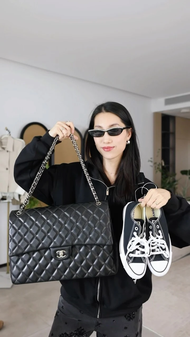 Black zip hoodie styled with embellished dark gray pants, black sneakers, and a quilted shoulder bag.