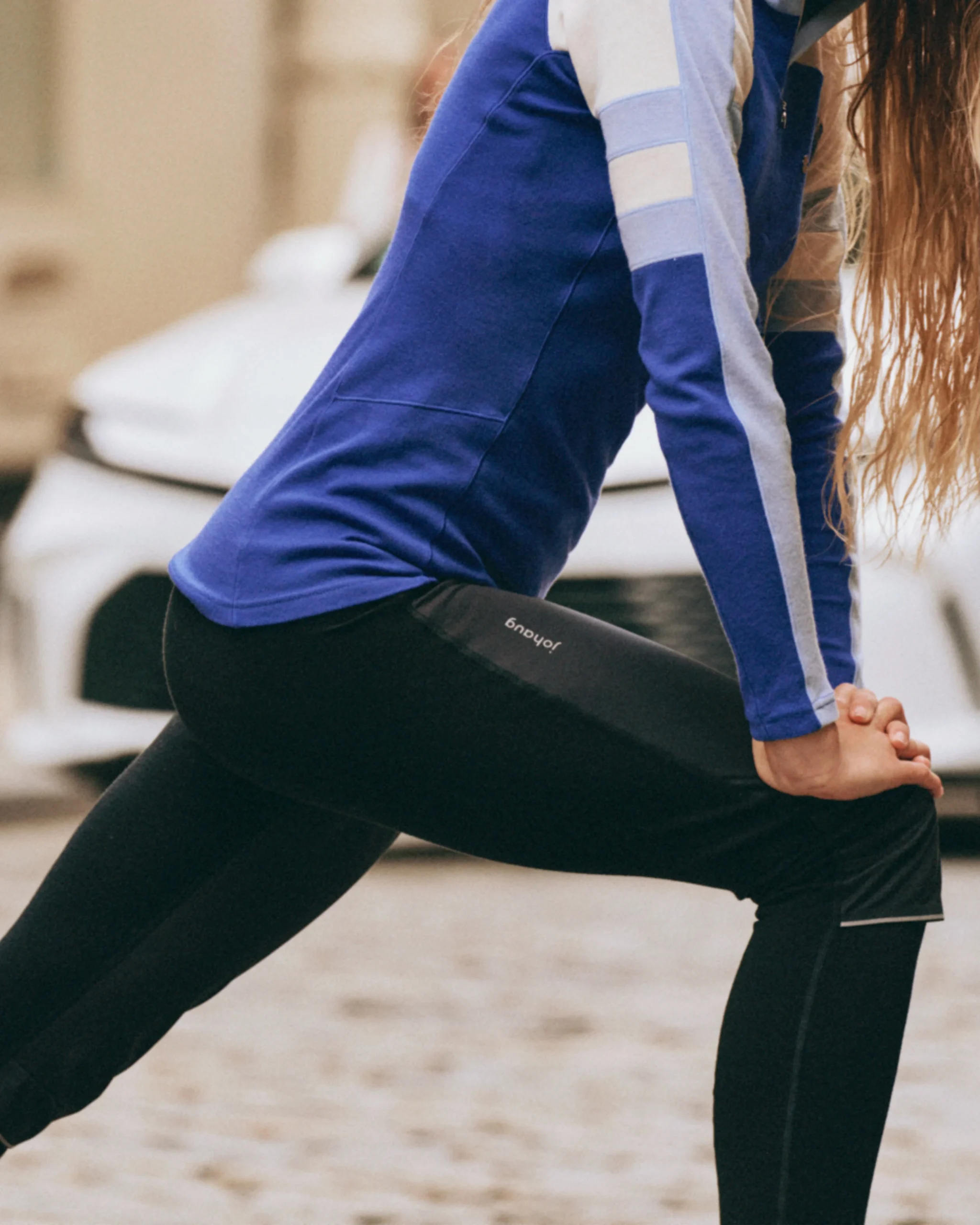 Person stretching in a blue color block long-sleeve top and black reflective leggings.