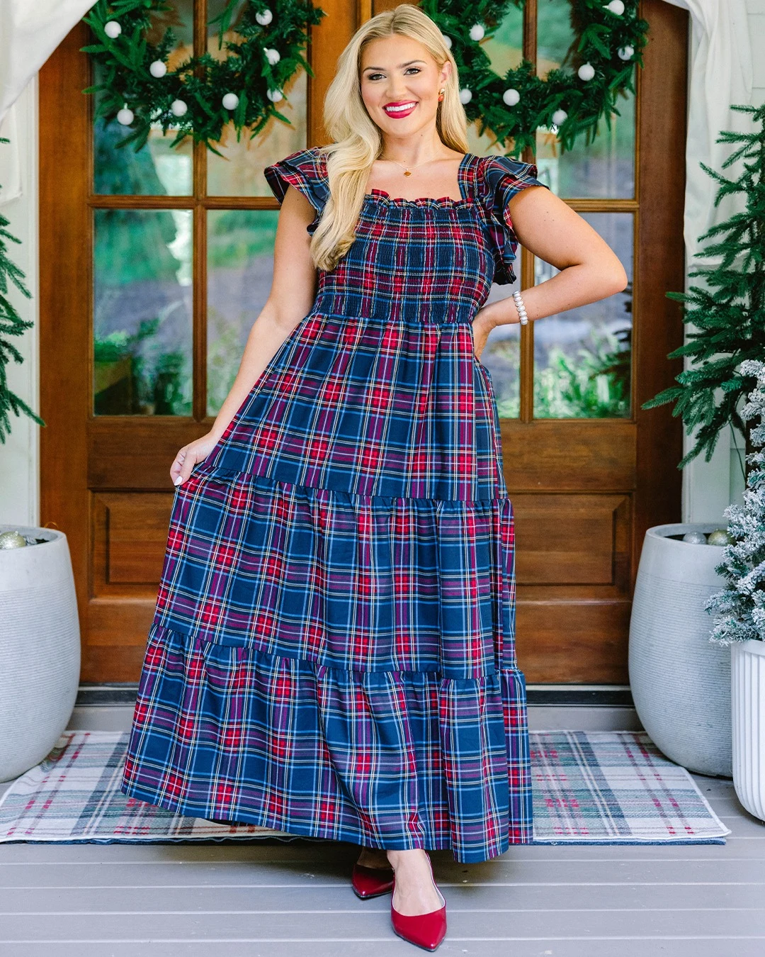 Floor-length blue plaid tiered maxi dress with smocked bodice and red pointed-toe shoes.