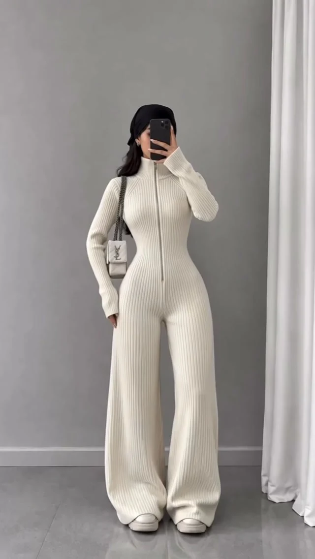 Fitted ivory ribbed jumpsuit with wide legs, white sneakers, and a chain-strap shoulder bag.