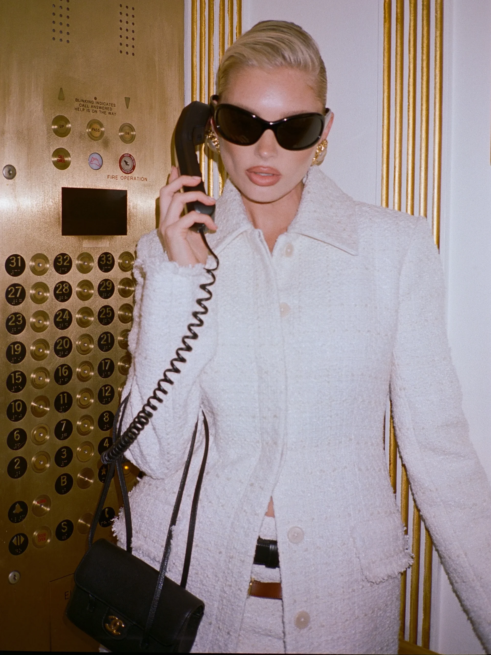 Pale ivory textured jacket and matching skirt worn as a monochromatic set with a dark belt.
