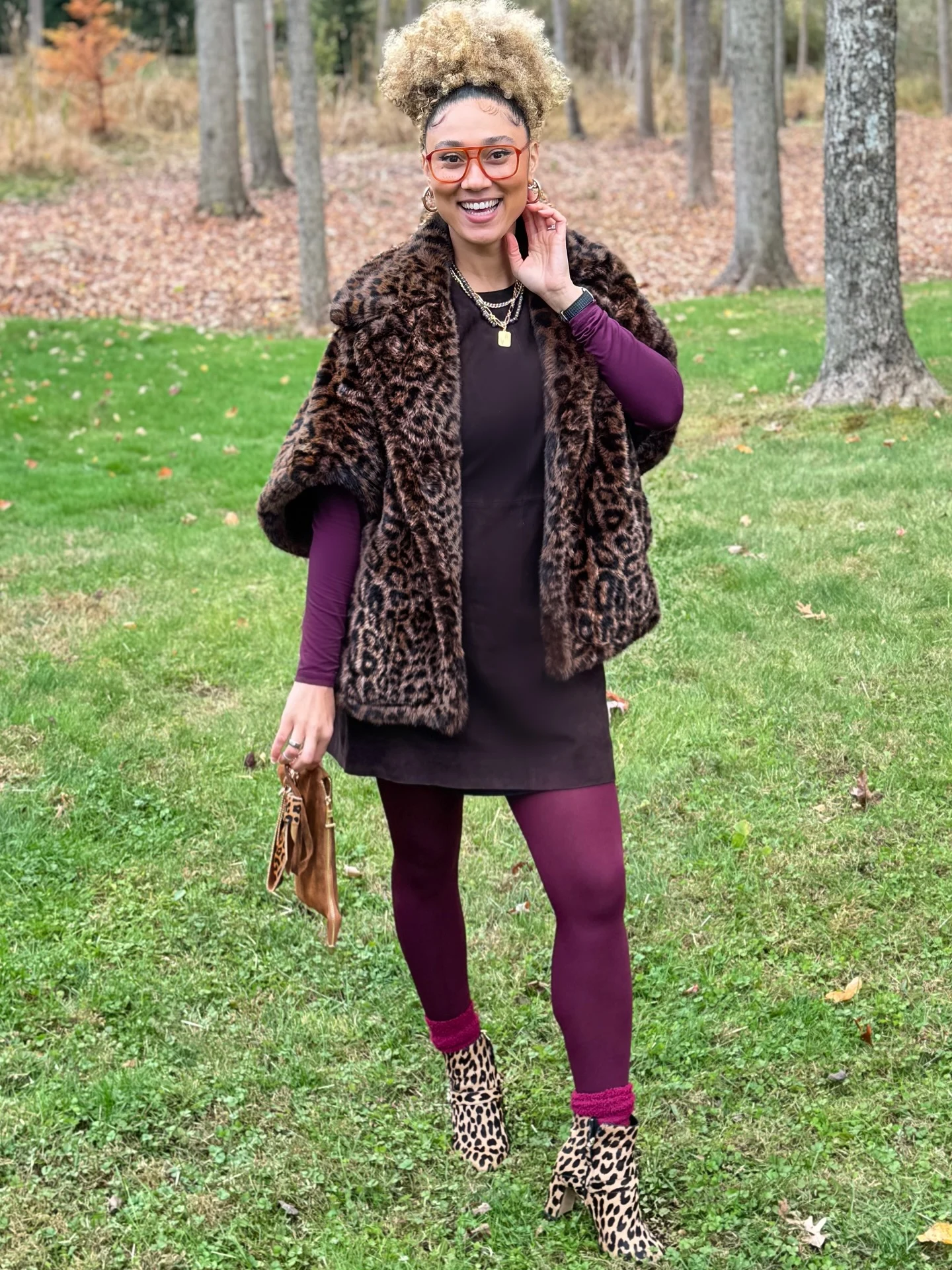 Leopard-print cape layered over a black tunic with plum leggings, magenta socks, and leopard boots.