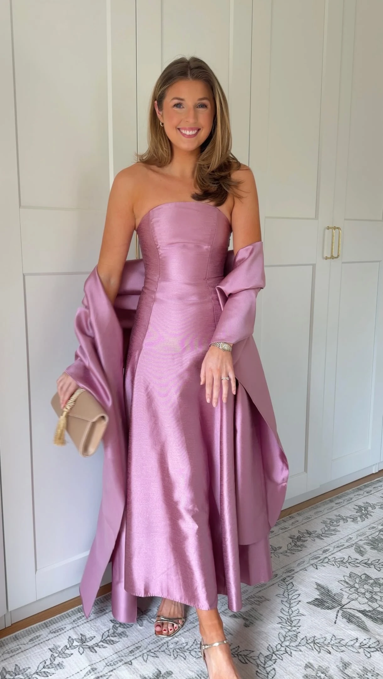 Woman in a strapless mauve gown with a matching draped shawl, metallic heels, and beige clutch.