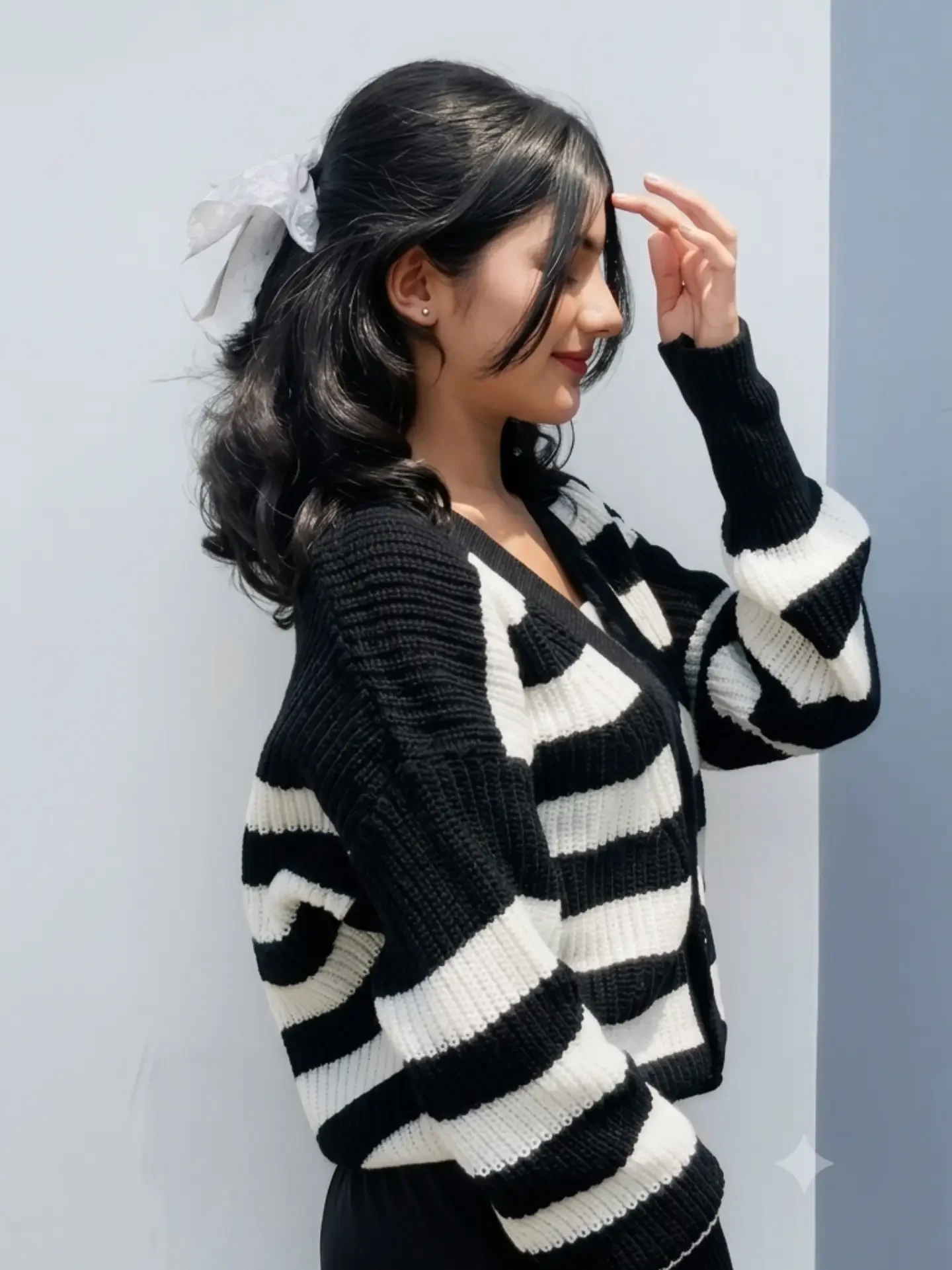 Loose black and white horizontally striped knit cardigan over dark top, light wash wide leg jeans, white sneakers