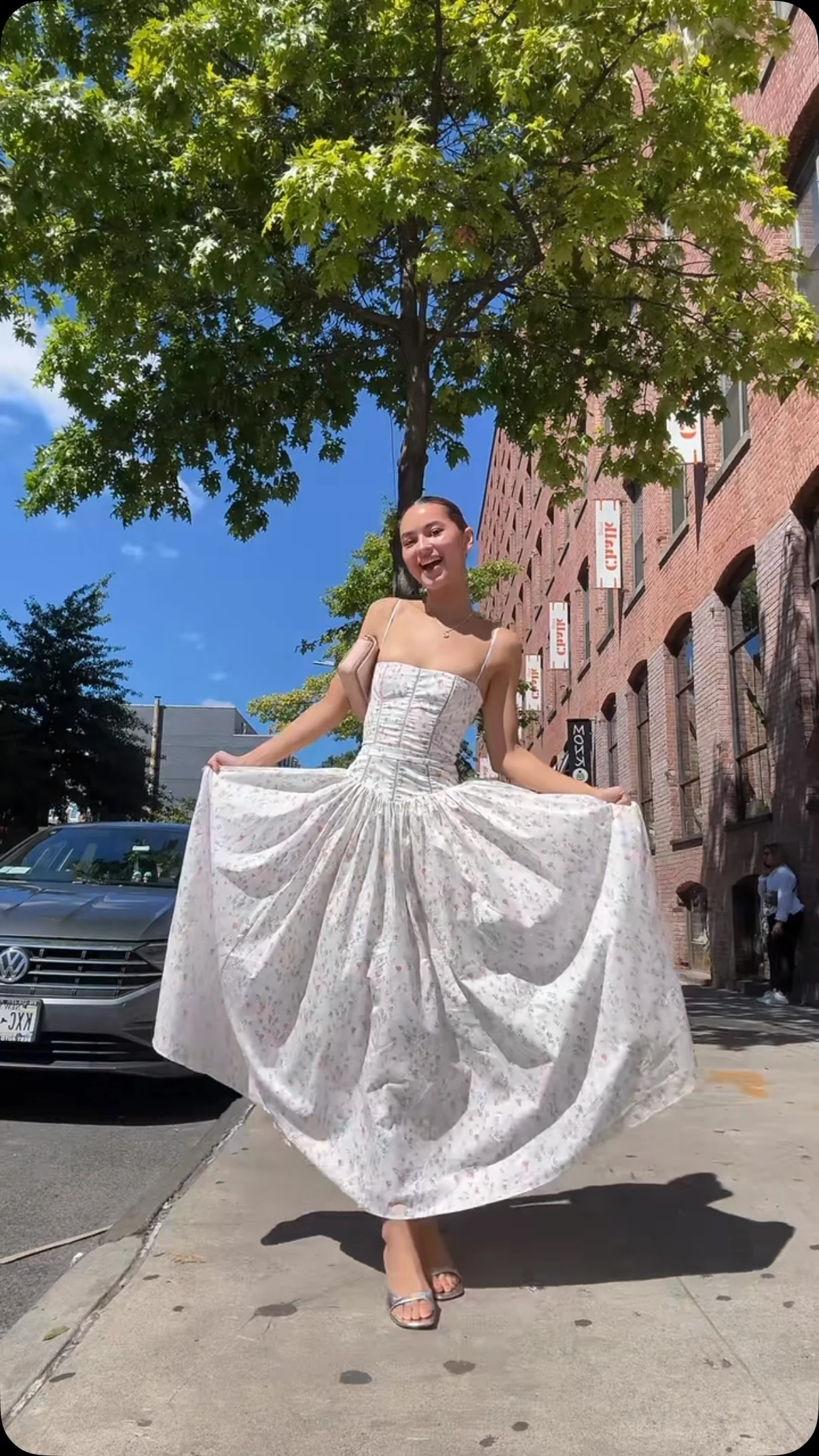 Woman wearing a white floral maxi dress with spaghetti straps and a fitted corset bodice.