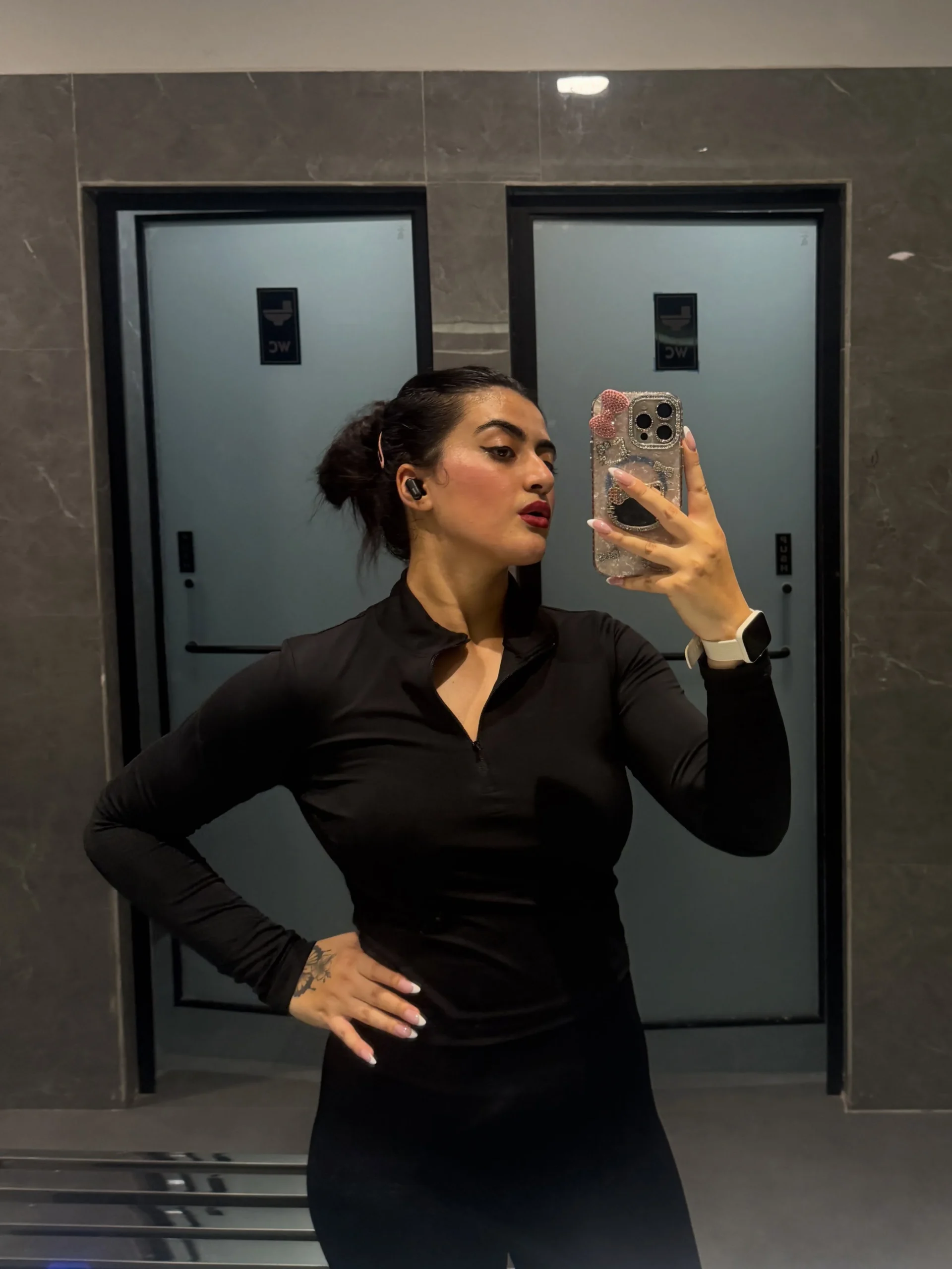 Person wearing a fitted black quarter-zip long-sleeve top, black leggings, and a light smartwatch.