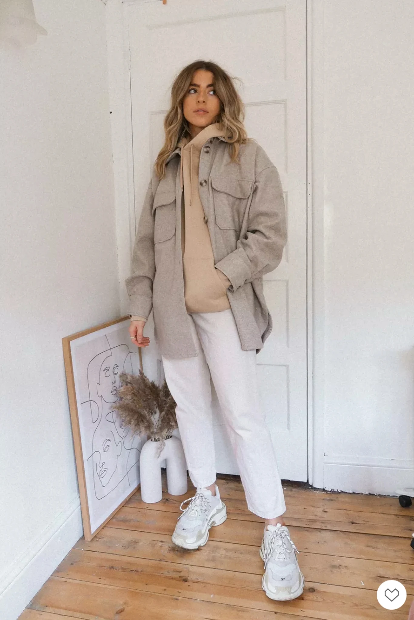Woman wearing a relaxed pullover hoodie with slim pants and casual sneakers.