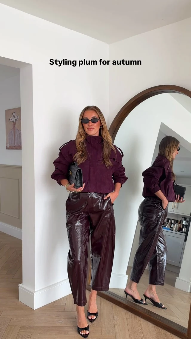 Deep plum cropped high-neck bomber jacket worn with matching plum wide-leg trousers.