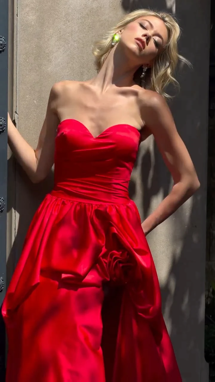 Red strapless satin ballgown with sweetheart neckline, ruched bodice, and sculpted hip detail.