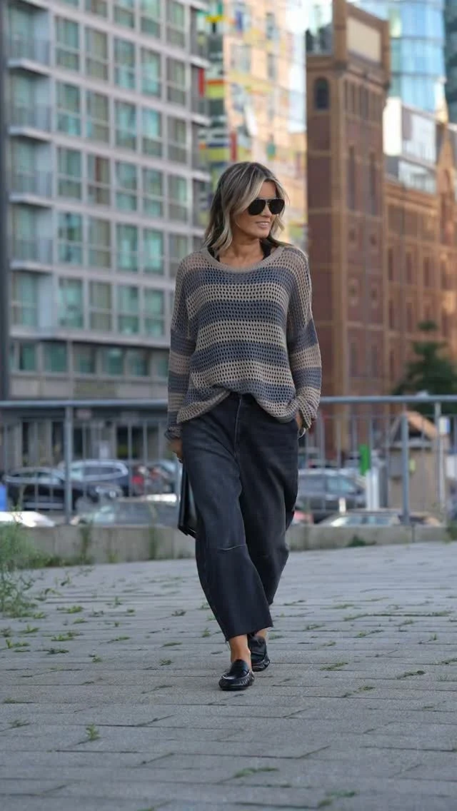 Loose striped open-knit sweater worn with dark wide-leg cropped pants, black flats, and sunglasses.