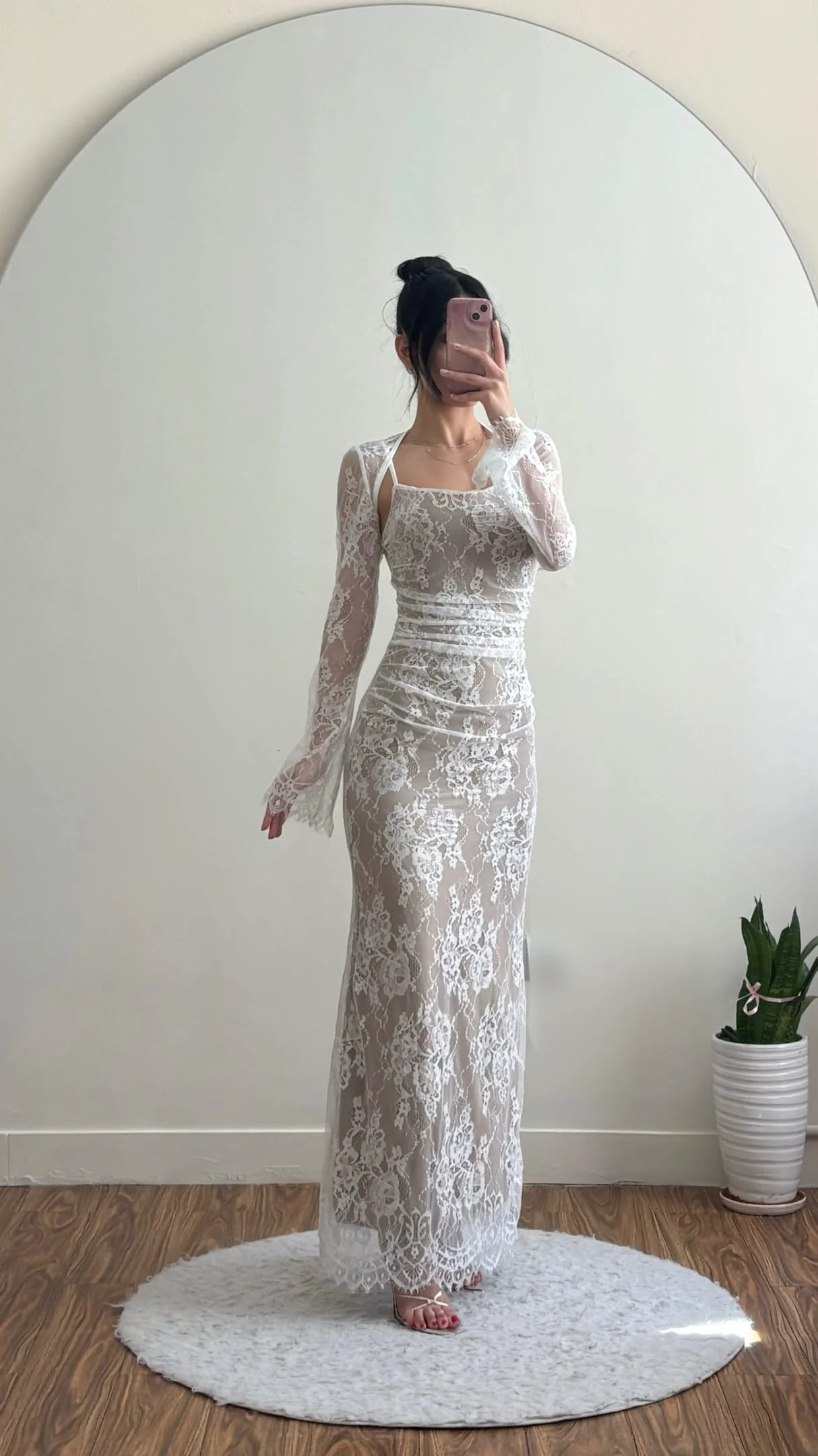 Long white floral lace dress with sheer sleeves, square neckline, ruched waist, and nude slip underneath.