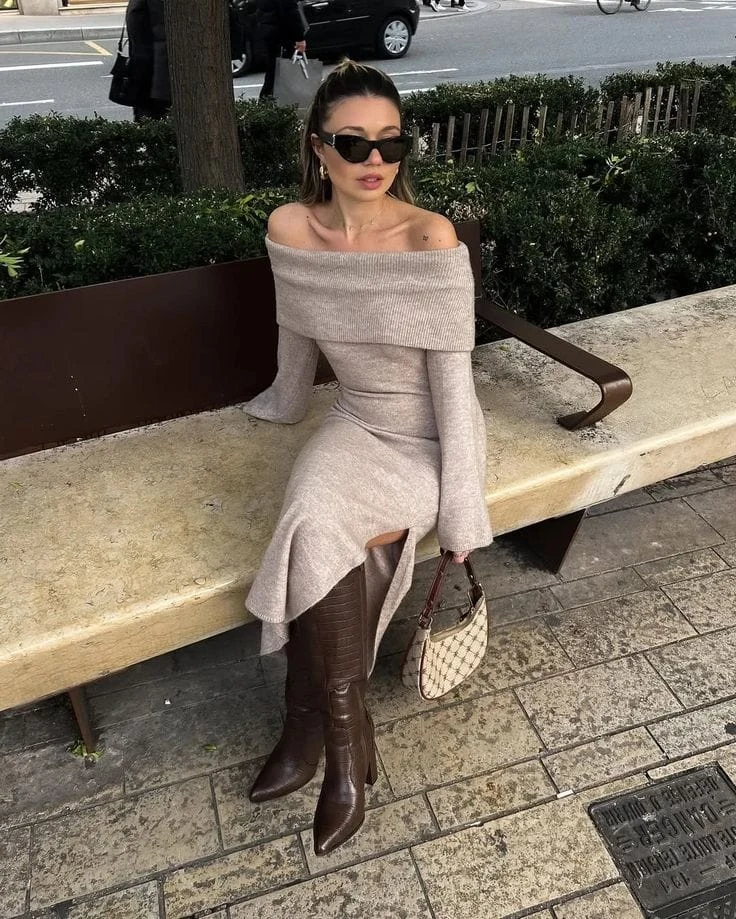 Taupe off-the-shoulder sweater dress with croc-embossed brown knee-high boots and a patterned mini bag.