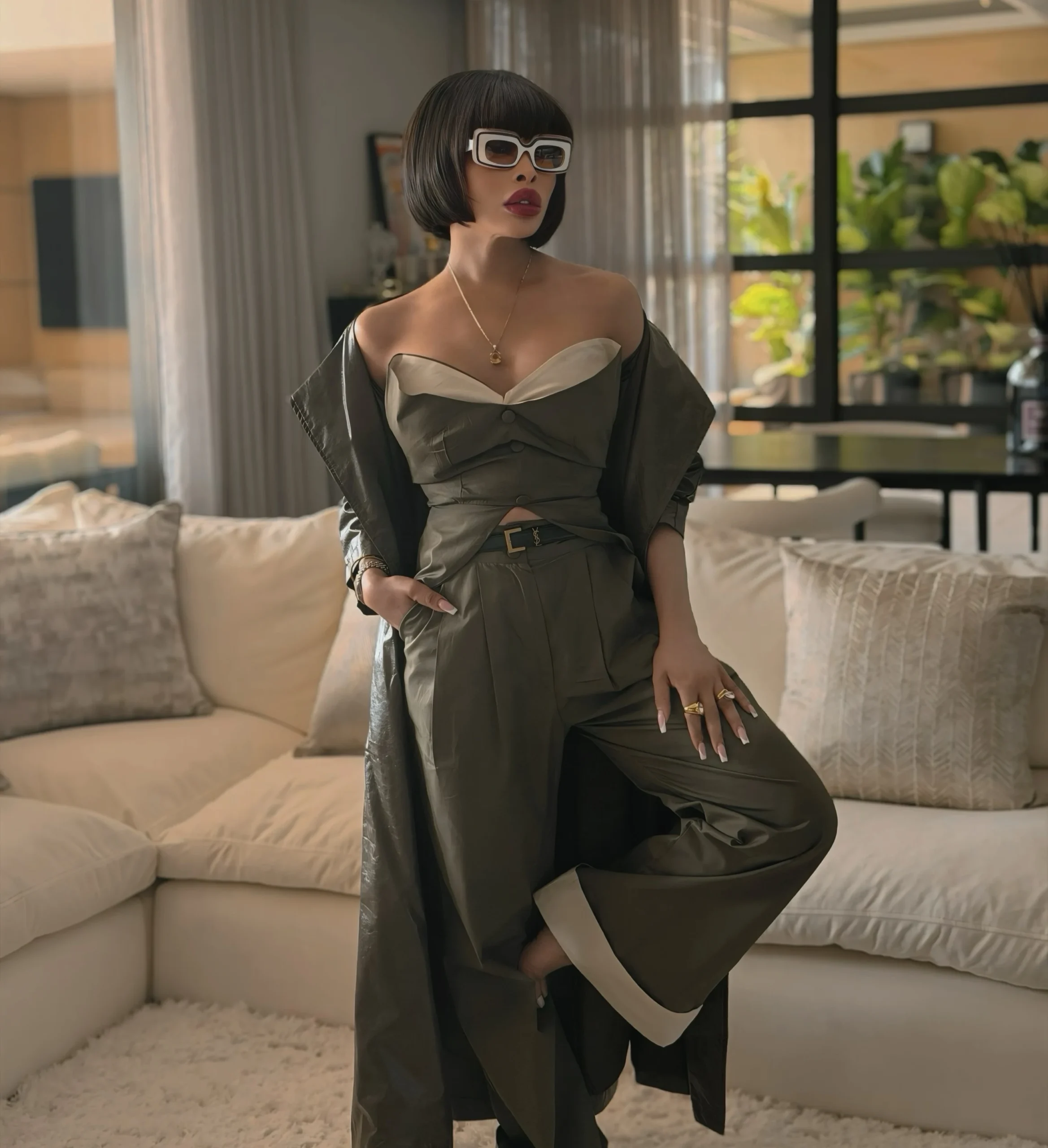 Olive strapless sweetheart top with matching wide-leg pleated trousers and a long dark olive outer layer.
