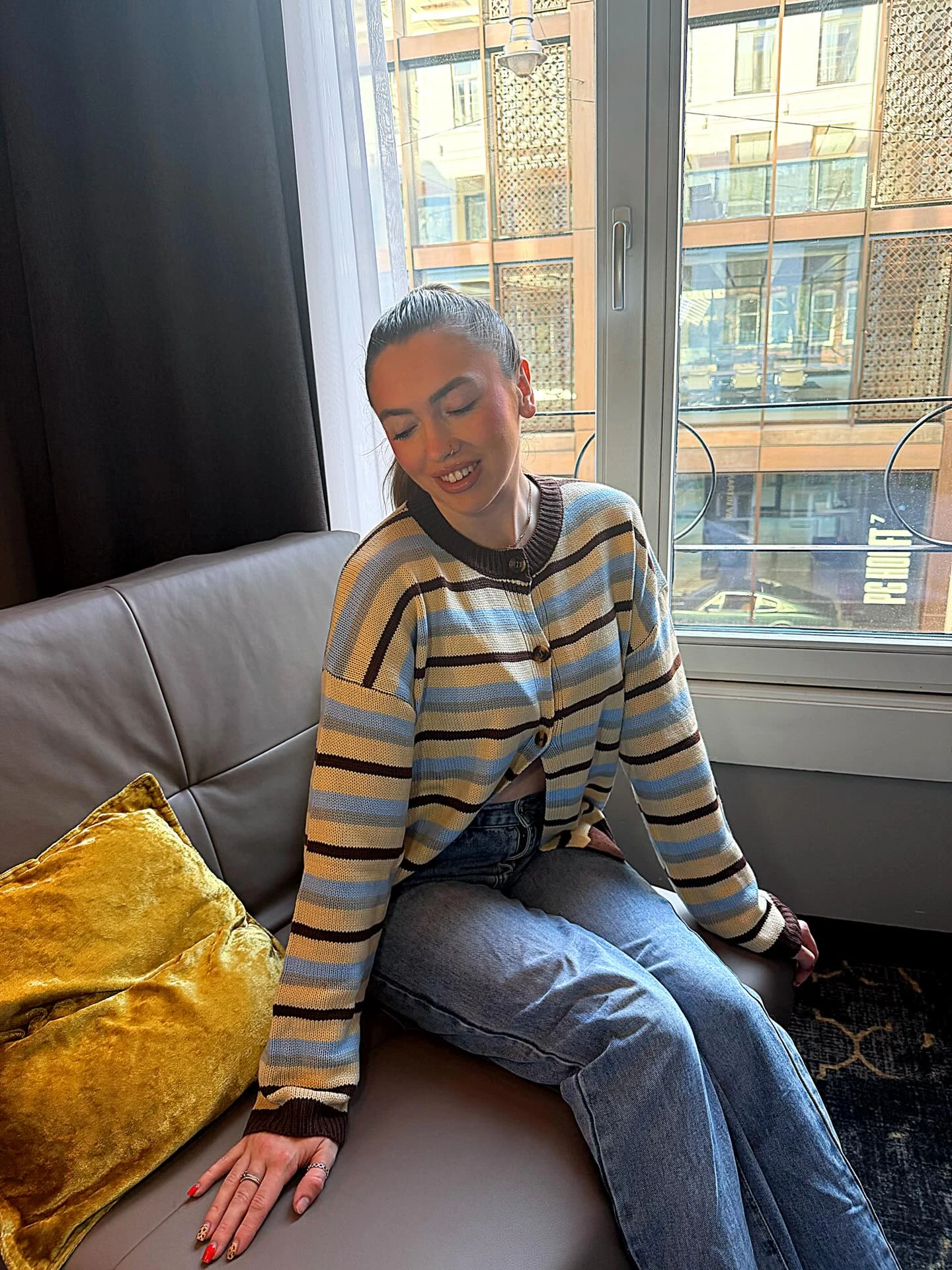 Oversized knit cardigan with horizontal stripes in cream light blue and brown with ribbed brown collar cuffs and buttons, light wash blue denim jeans