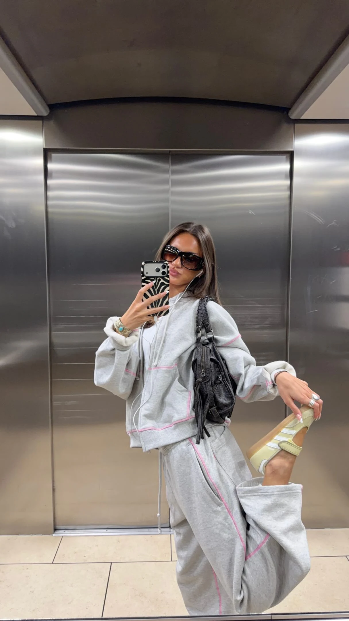 Pale yellow long-sleeve top and matching Adidas Sambas styled with wide-leg jeans and a black bag.