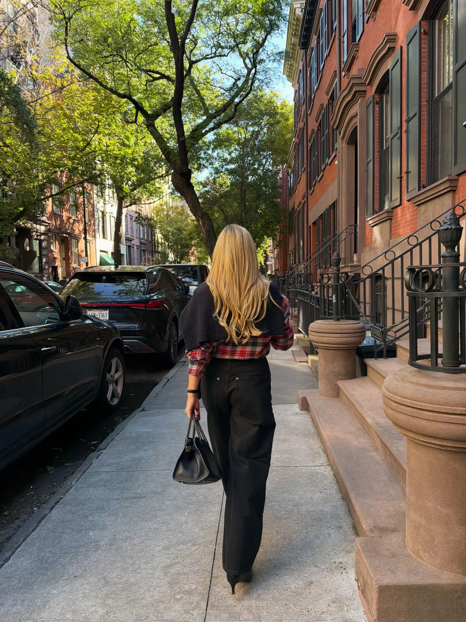 Red and black plaid flannel over black top, light-wash jeans, and black boots fall fair look.
