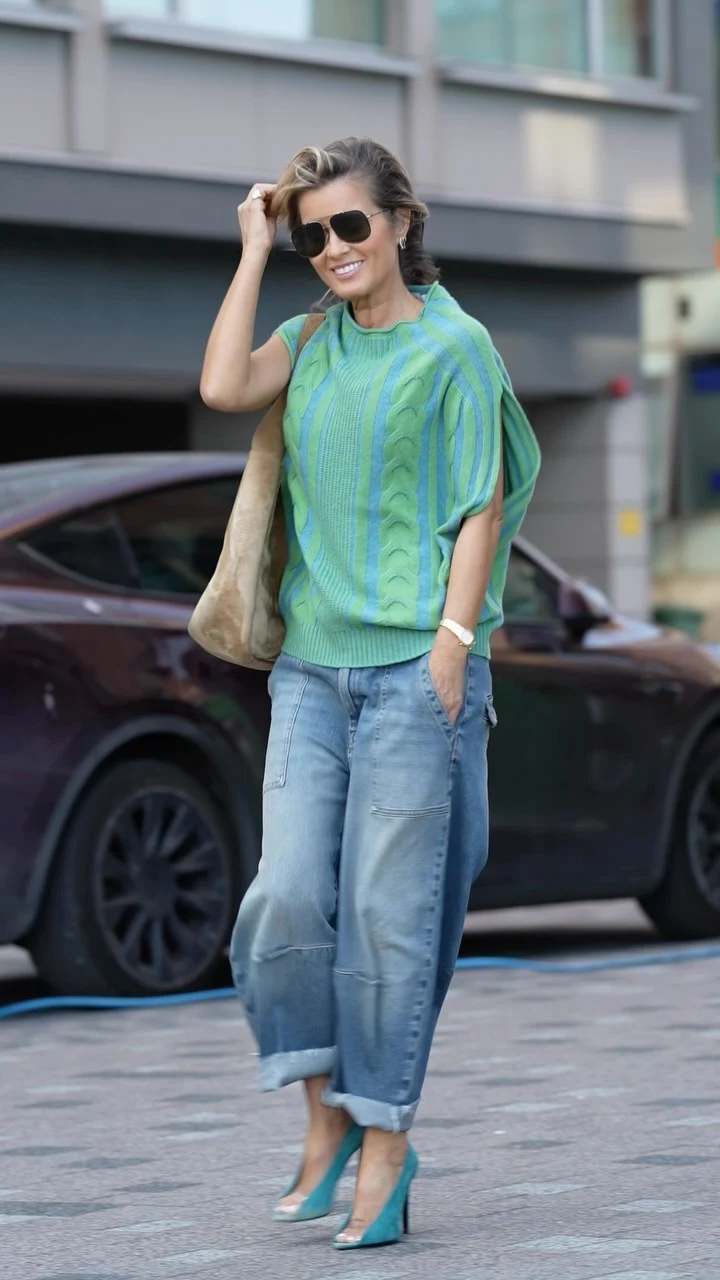 Striped cable knit sleeveless sweater worn with cuffed baggy jeans, teal heels, and a tan tote bag.