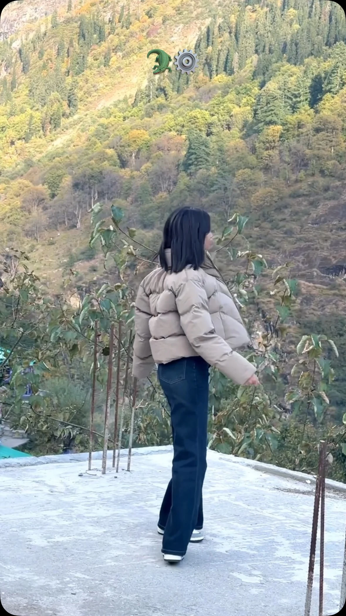Beige cropped quilted puffer jacket paired with dark blue flared jeans seen from behind outdoors.
