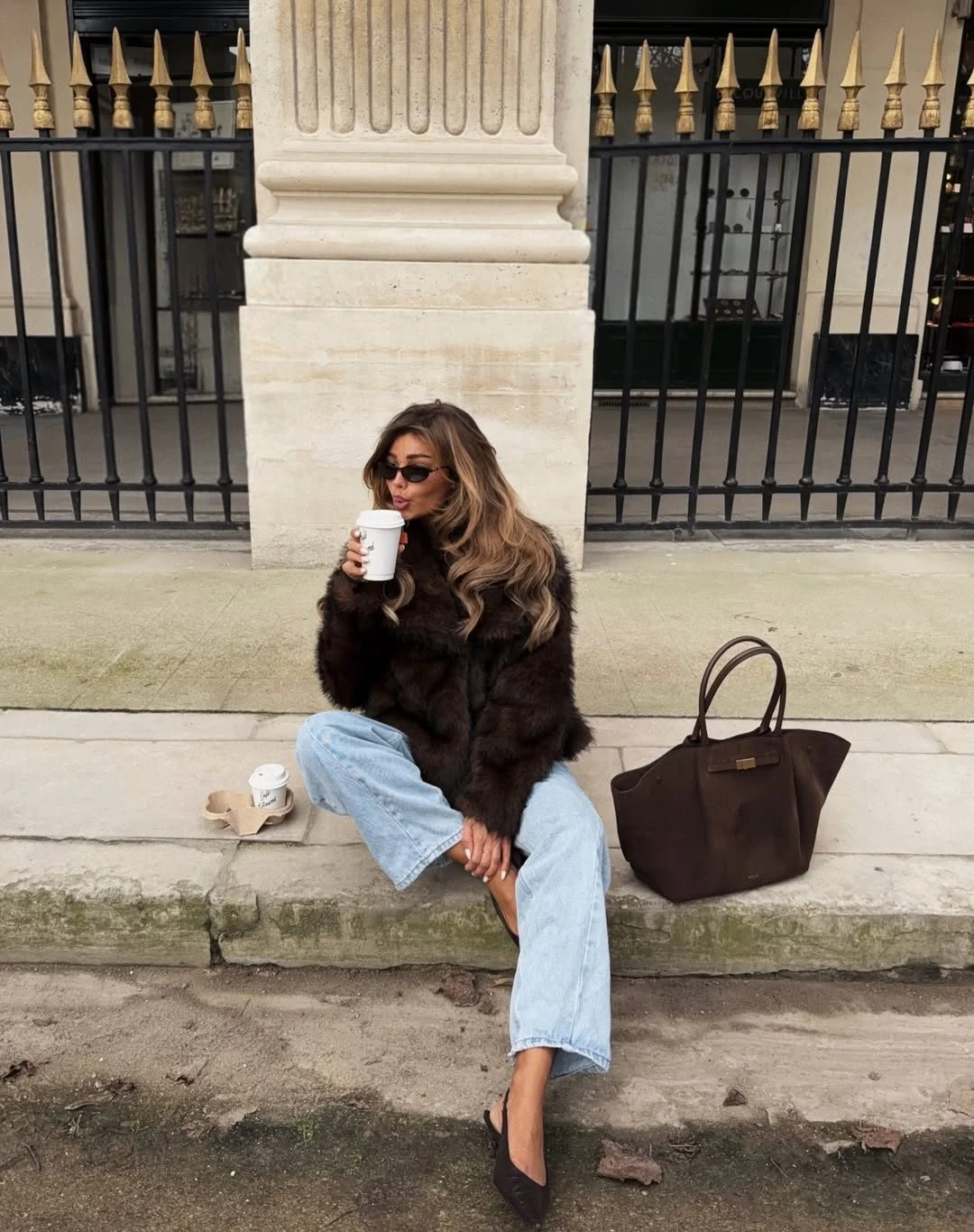 Chocolate brown faux-fur jacket over a black top, dark jeans, and sunglasses.