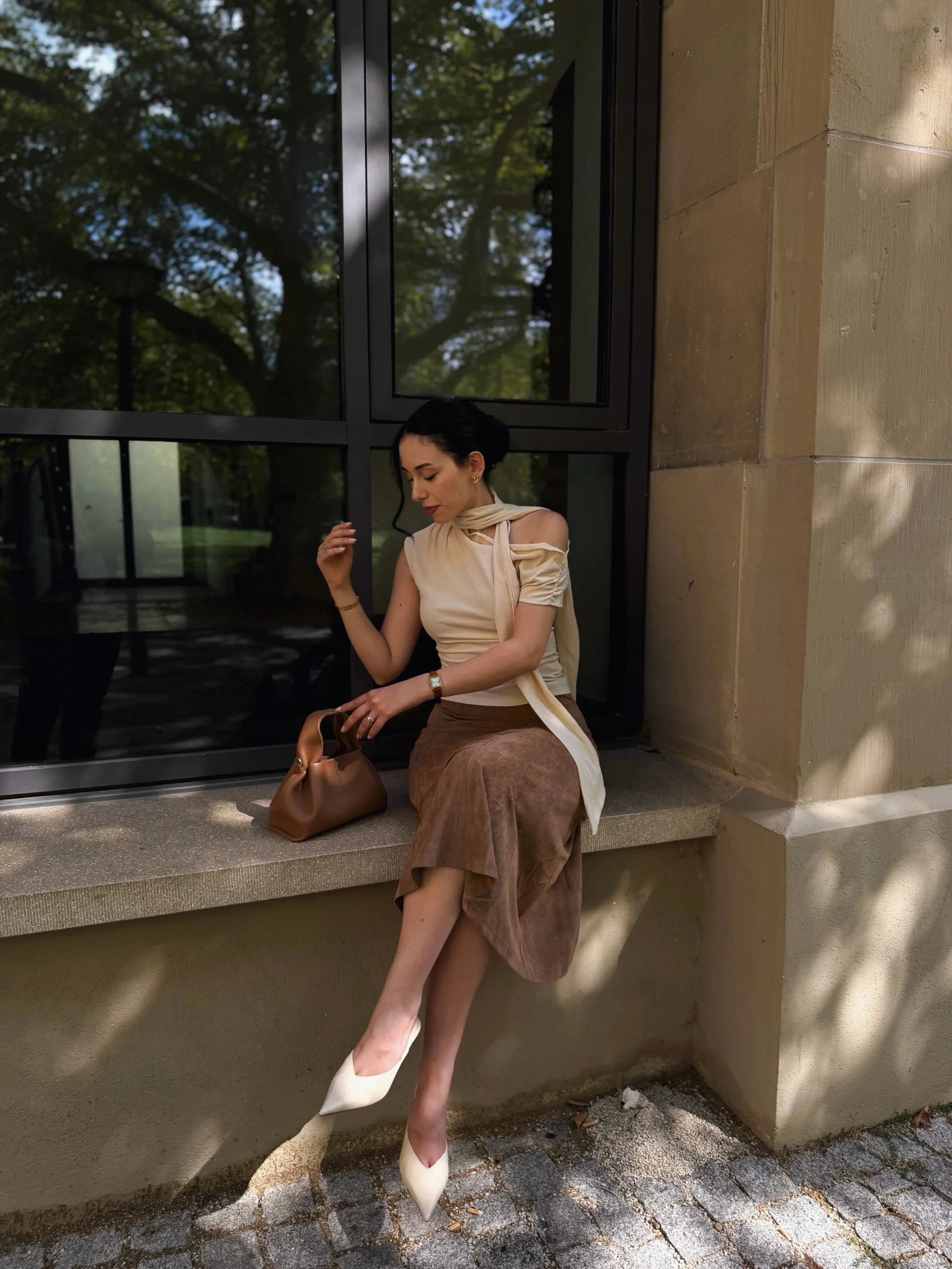 cream off-the-shoulder top, brown suede midi skirt, white pointed heels, brown leather handbag