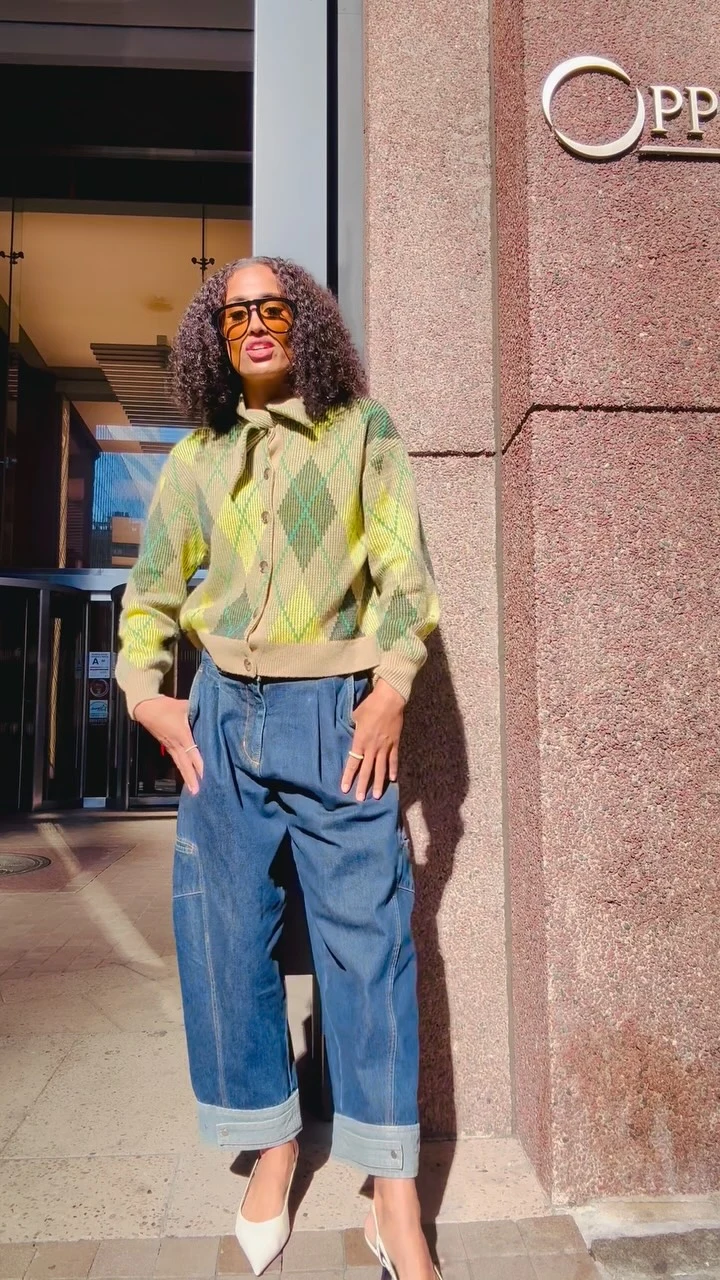 Woman in a cropped lime green and yellow argyle cardigan over a white top with light-wash jeans.