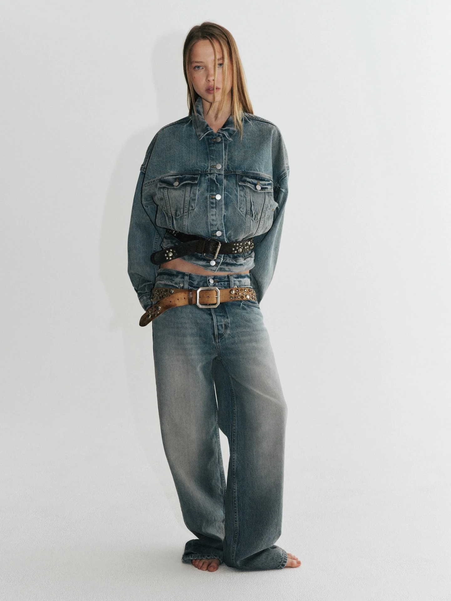 Boxy faded blue cropped denim jacket with wide-leg jeans and two layered belts at the waist.