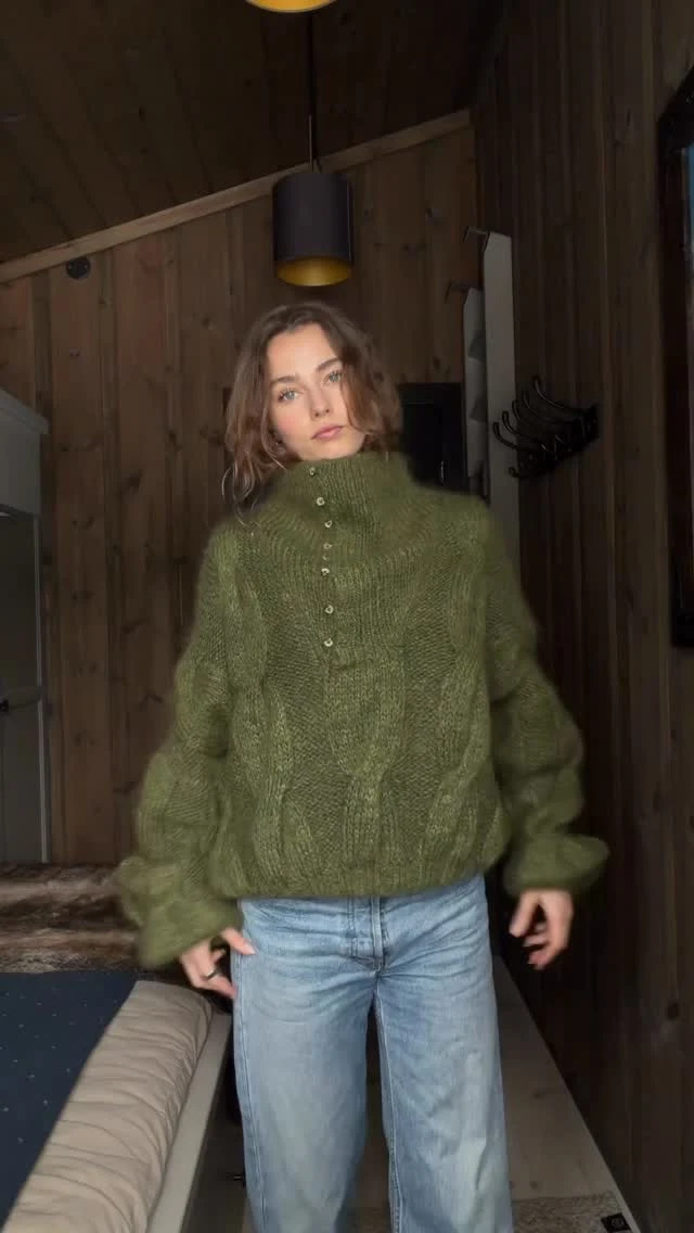 Oversized olive-green fuzzy turtleneck cable knit sweater paired with light blue wide-leg jeans.