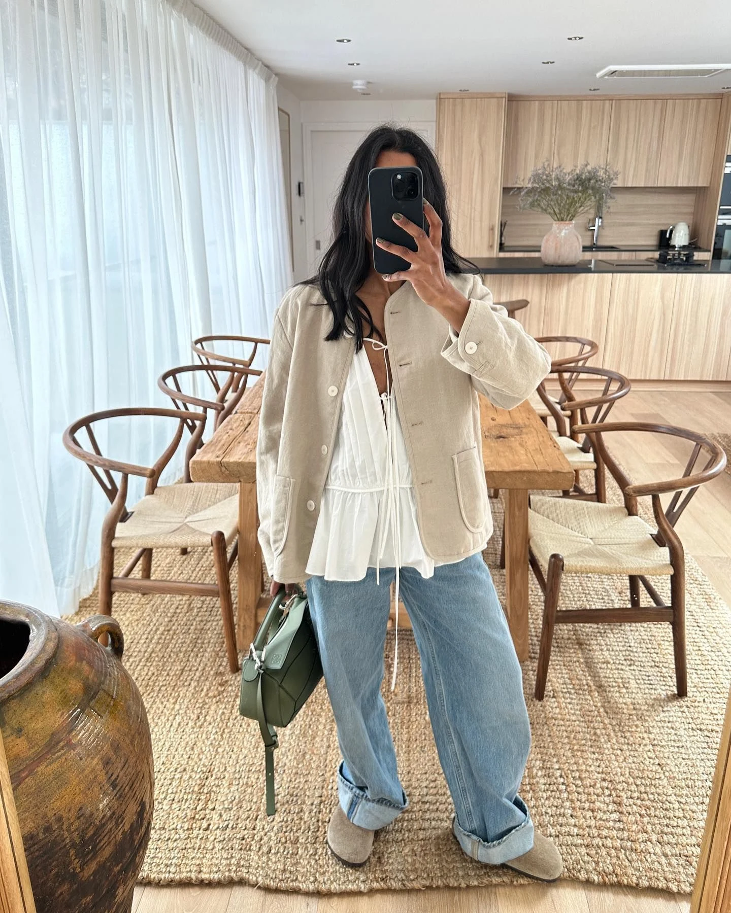 Monikh wearing a ruffled blouse, jacket, and Birkenstock Boston clogs in a polished casual look.