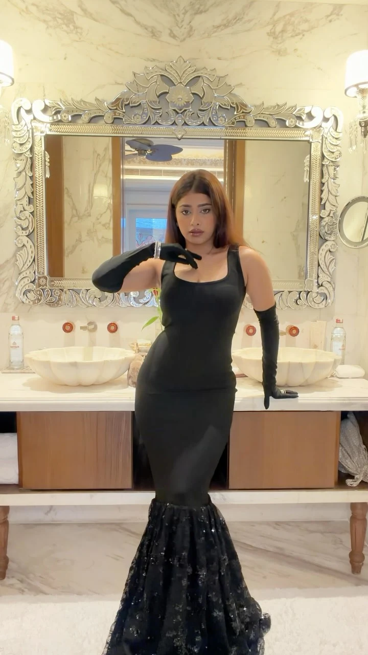 Woman in a black sleeveless square-neck gown with a flared hem and long black gloves.