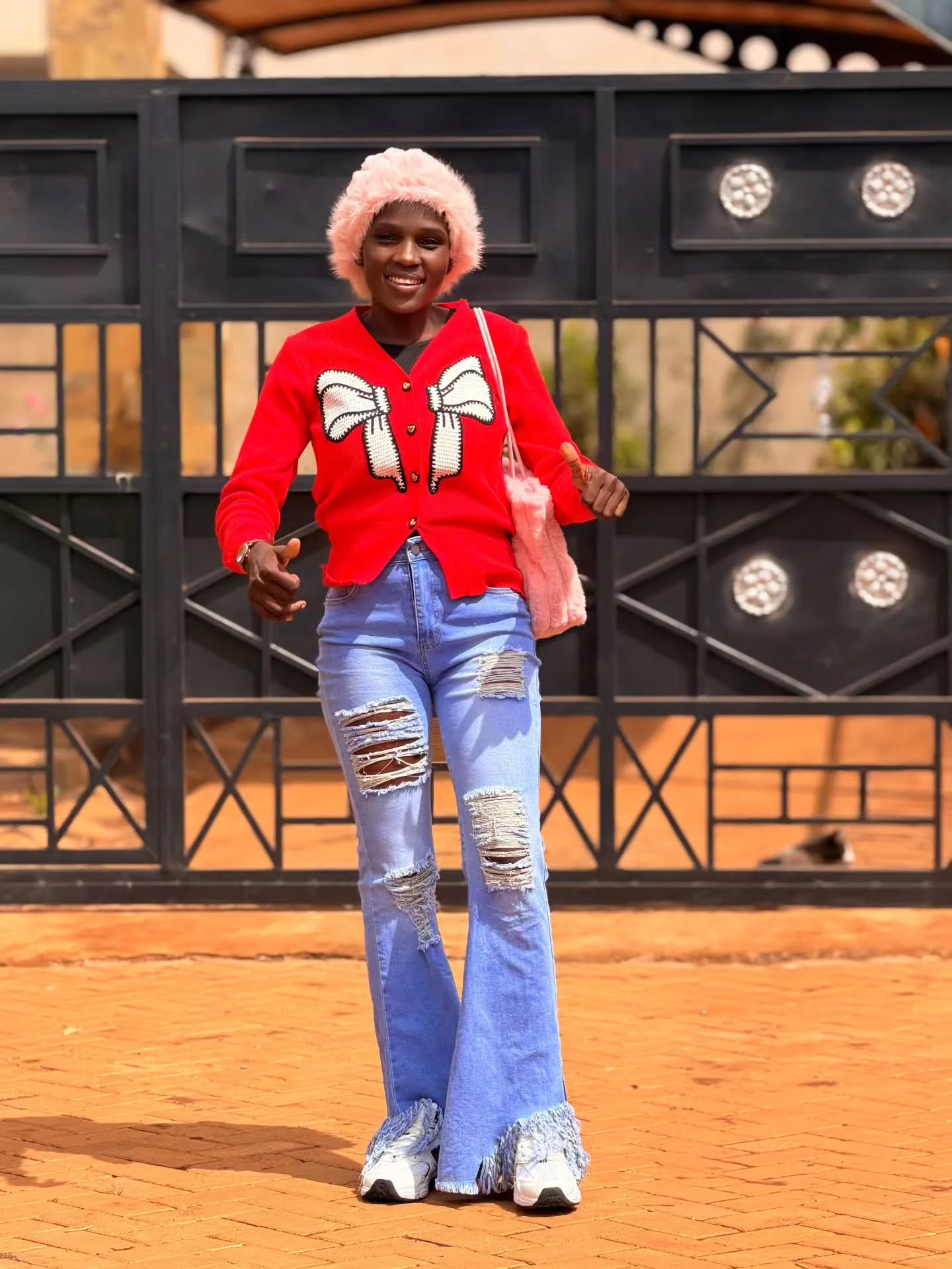 Bright red bow cardigan layered over a white top with light-wash ripped flare jeans.