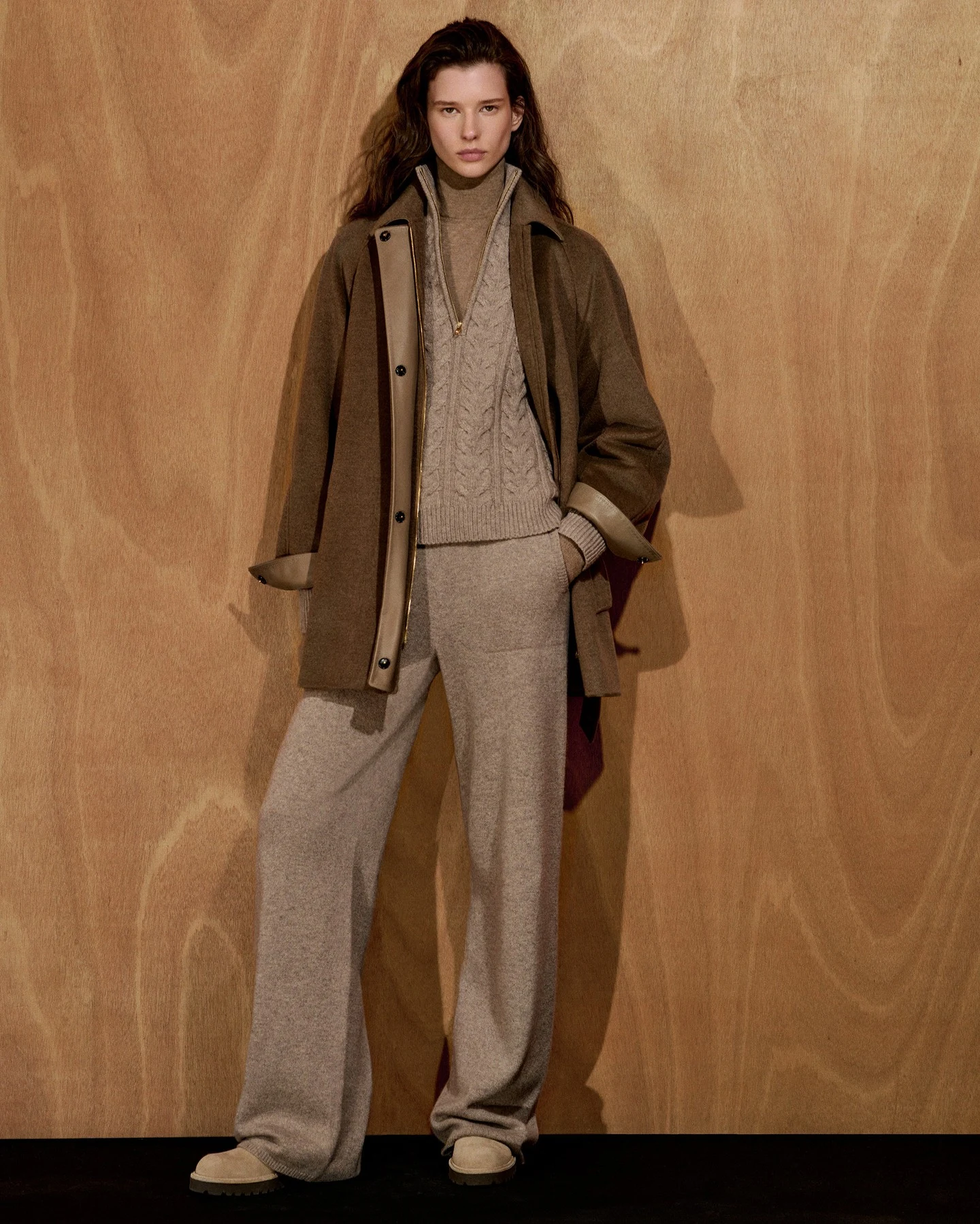 brown wool coat with leather trim, beige turtleneck under cable knit half-zip sweater vest, matching loose knit trousers, light platform shoes