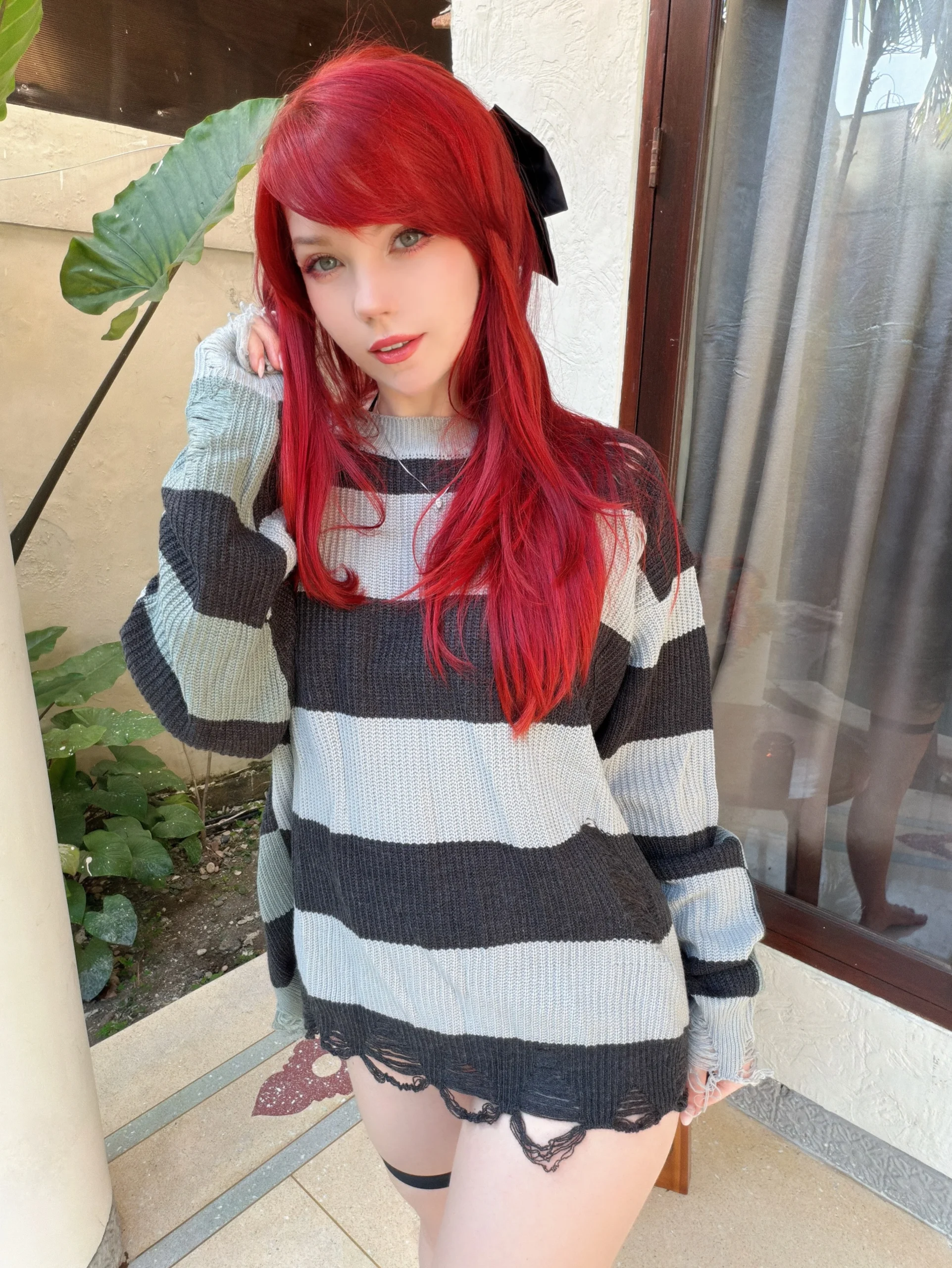 Oversized black-and-white striped sweater with fringed hem worn over short black bottoms.