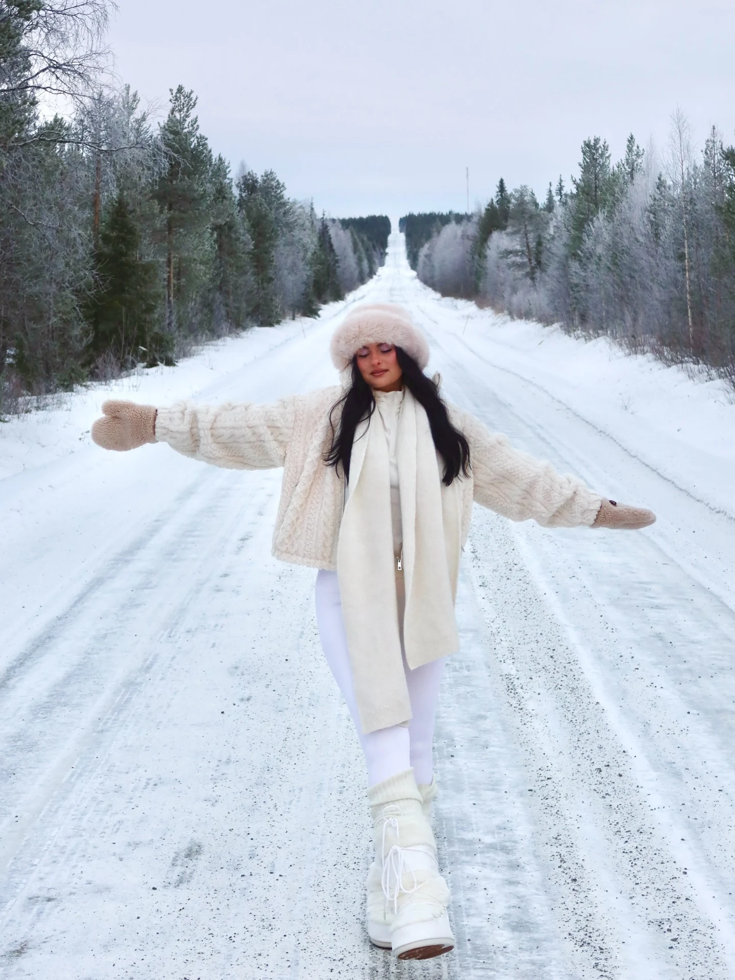 oversized cream cable knit sweater jacket, light pink fuzzy fur hat, long cream scarf, white leggings, white snow boots, beige fuzzy mittens