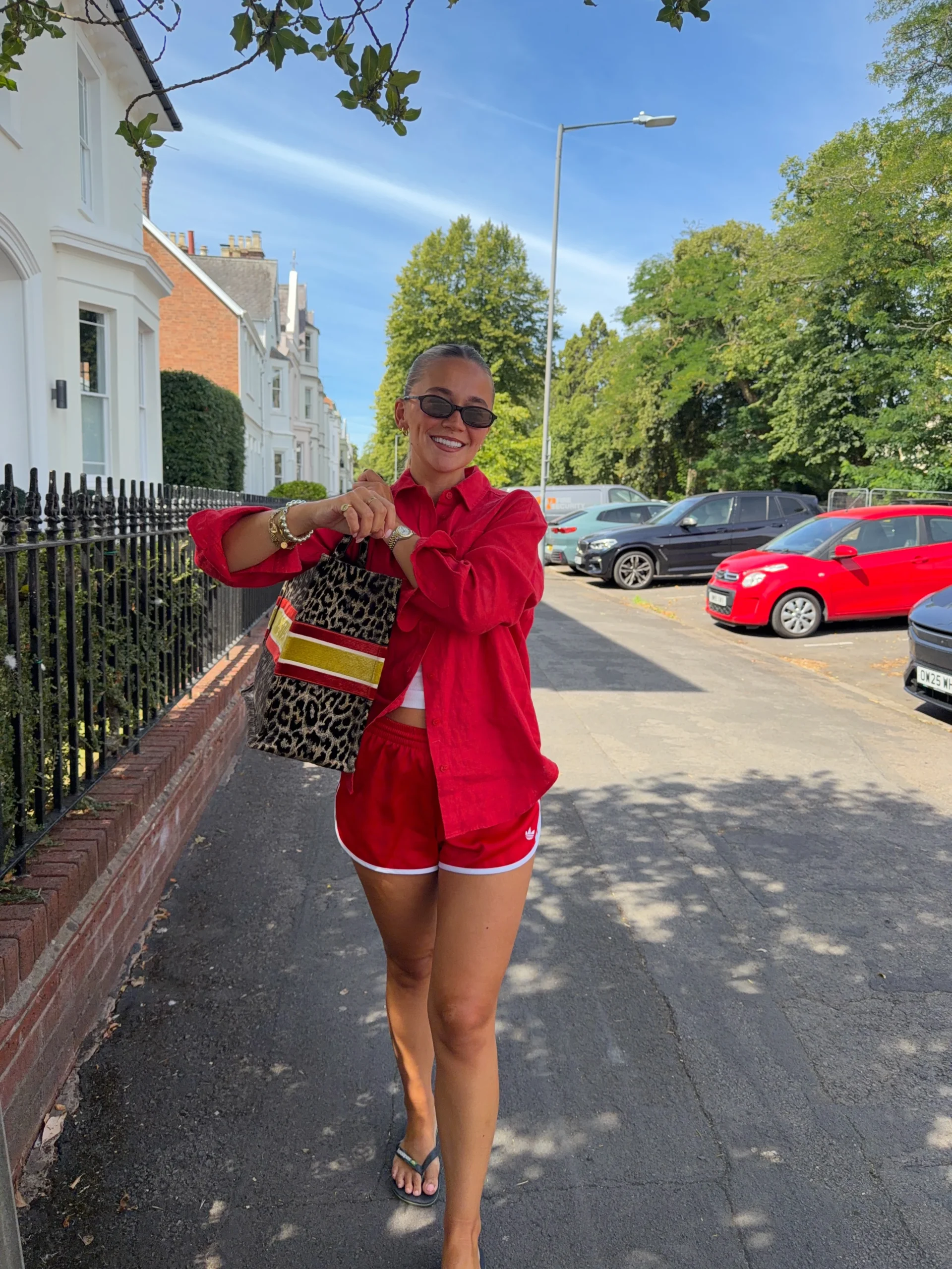 Person wearing a red button-front shirt and matching red shorts with white-edged hems outdoors.