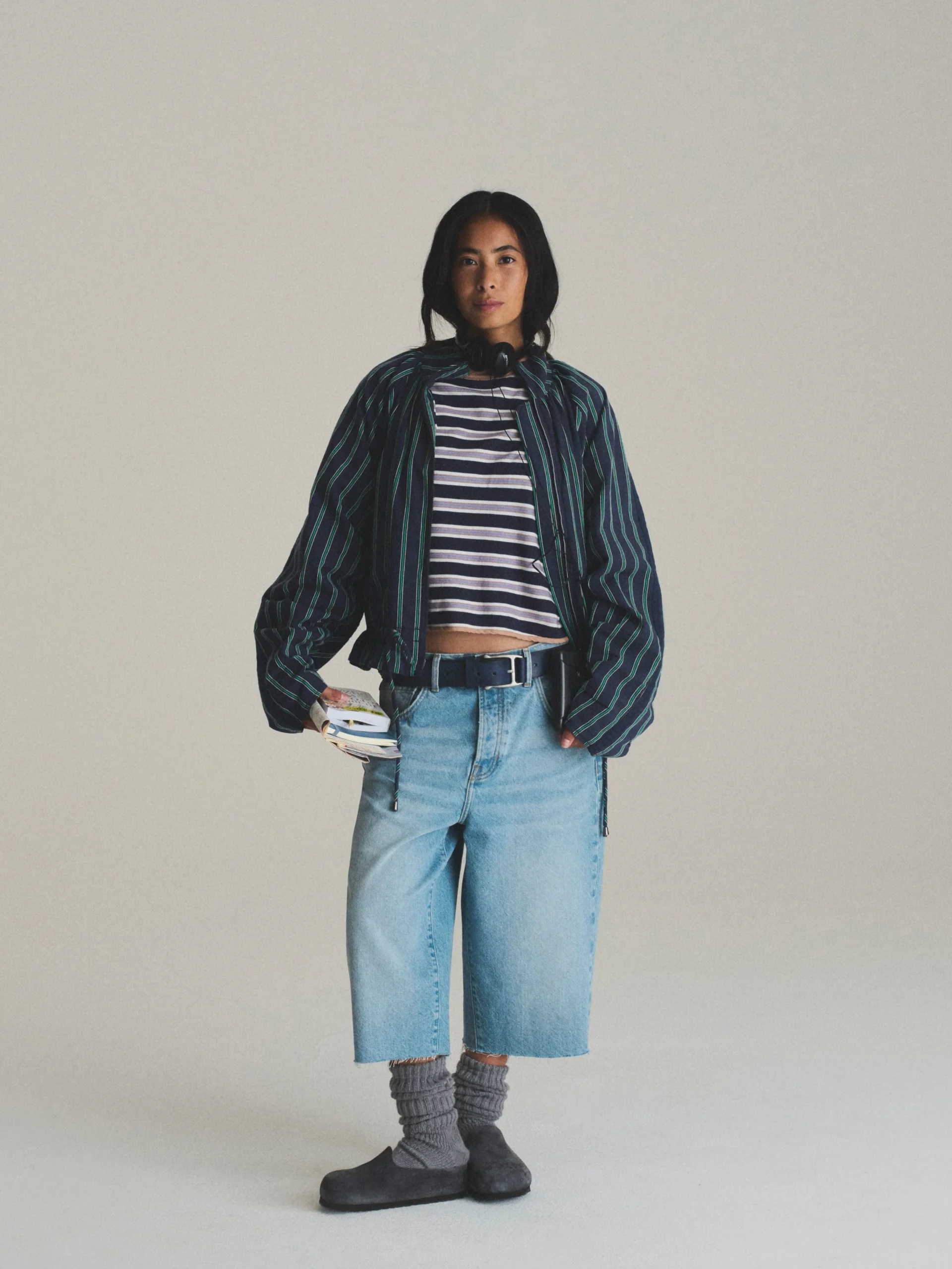 Person wearing a striped oversized jacket, cropped tee, wide-leg culottes, and dark gray Amsterdam clogs.