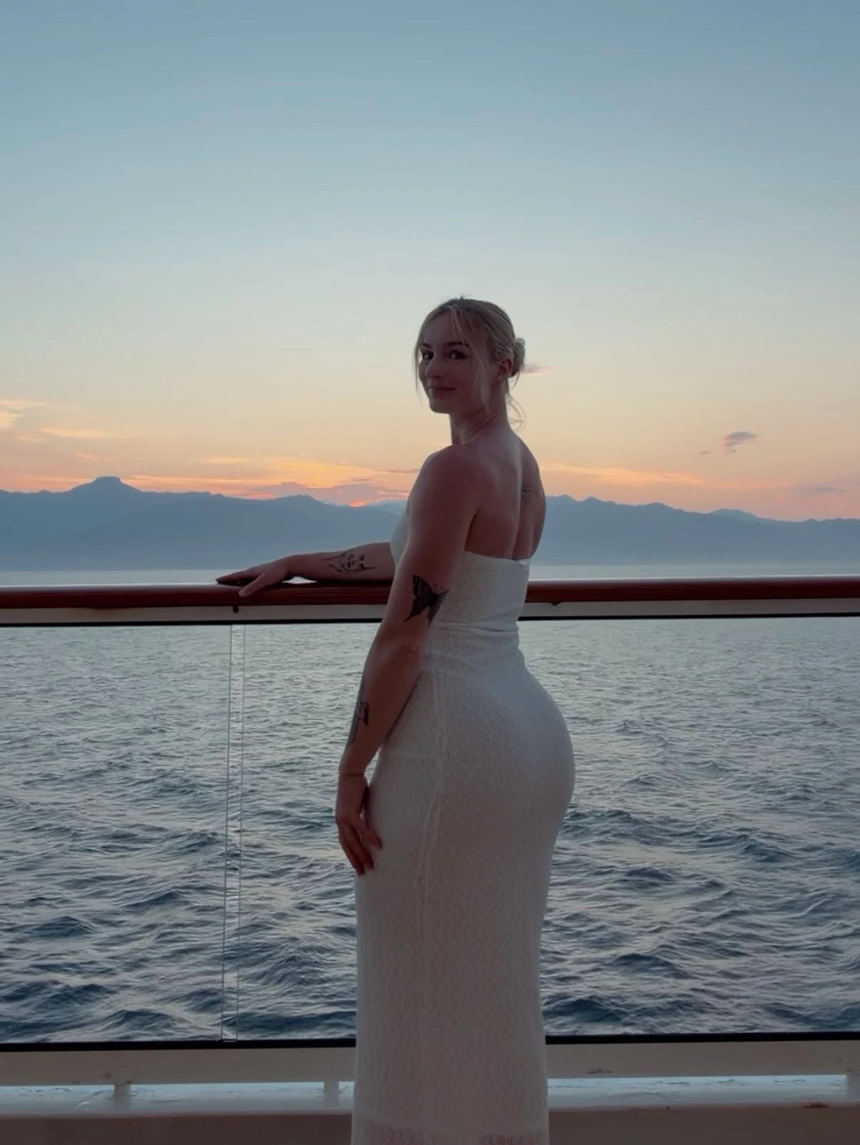 Woman wearing a white strapless form-fitting lace maxi dress on a cruise vacation.