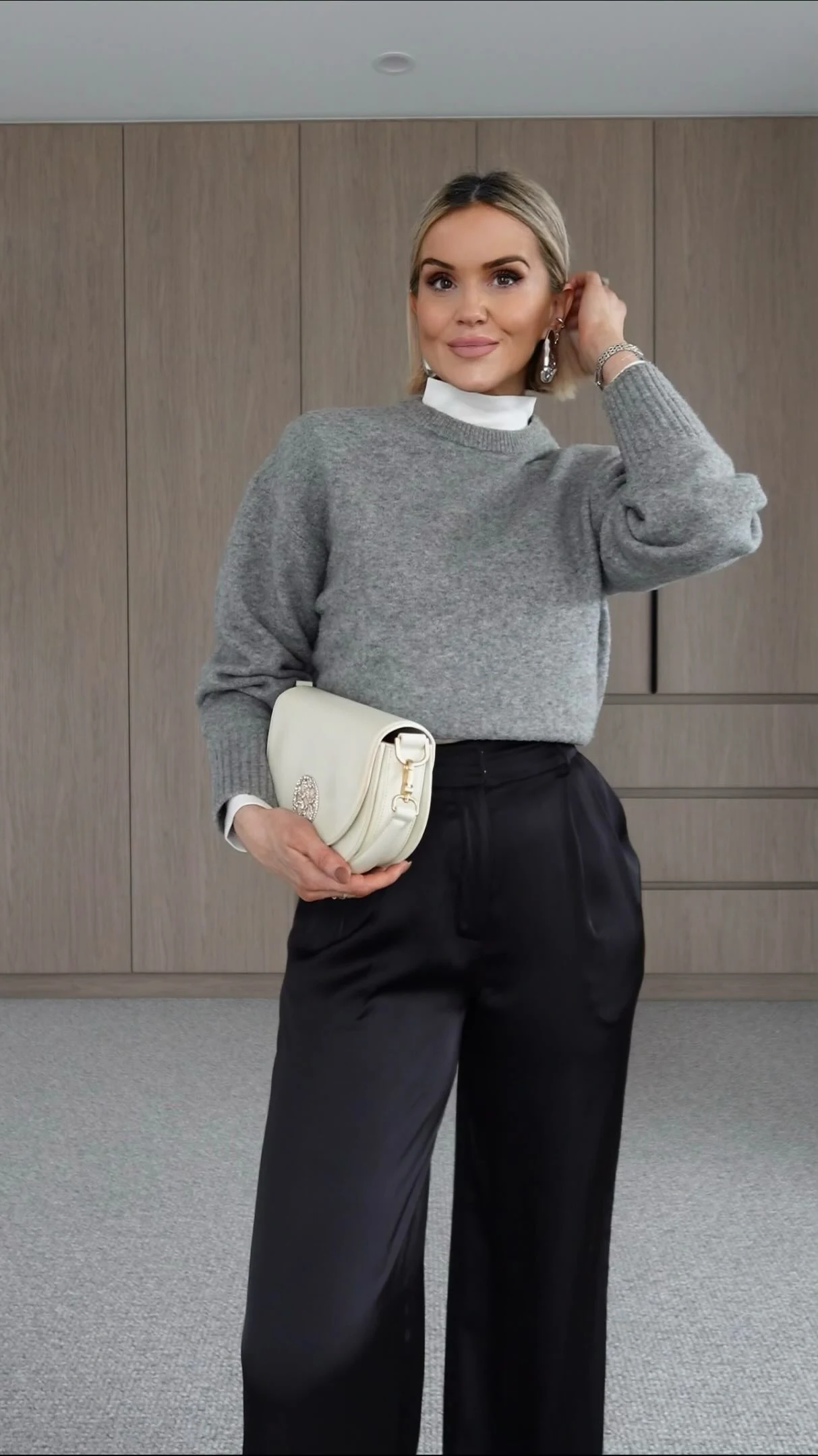 White turtleneck and cropped grey knit layered with black satin trousers and silver pointed flats.