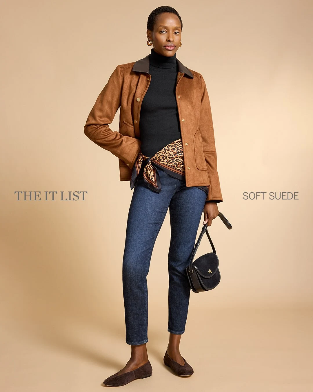 Woman in a cream knit cardigan, tan suede midi skirt, and a leopard-print baseball cap.