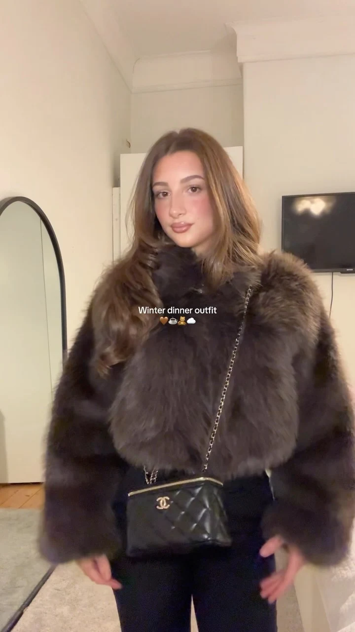 Voluminous dark brown faux fur jacket over all-black outfit with pointed heels and quilted chain bag.