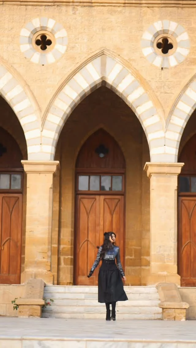 Fitted dark graphic top with high-waisted flared black skirt, dark tights, and ankle boots.