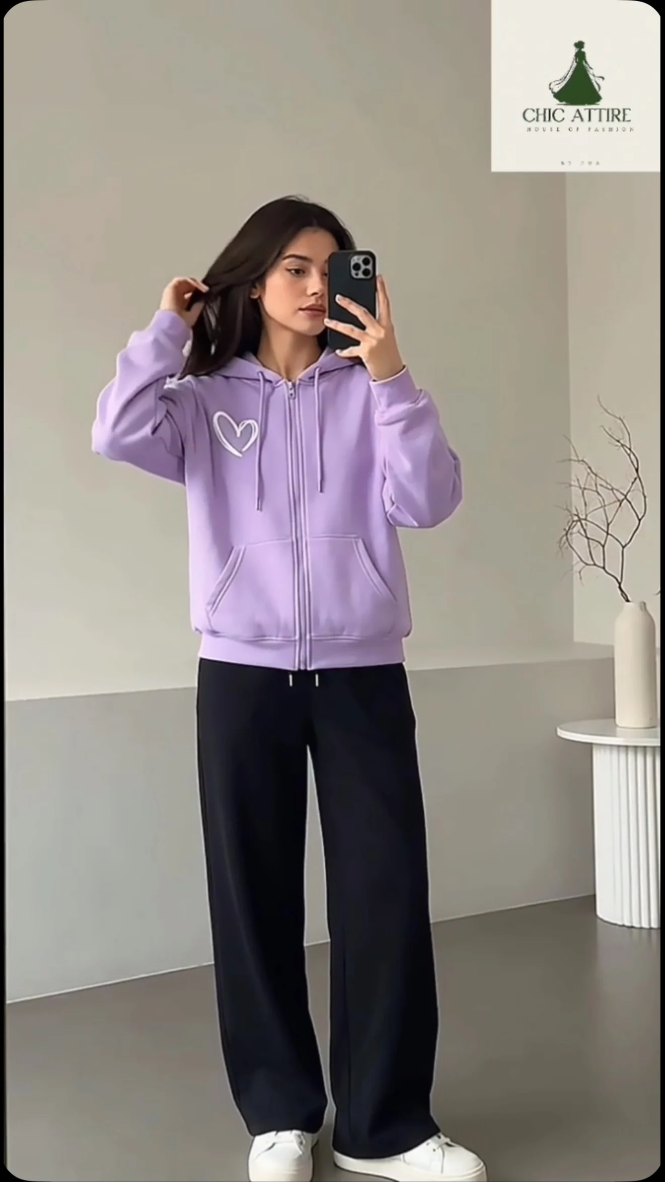 Light-purple zip-up hoodie with loose black trousers and white platform sneakers styled casually.