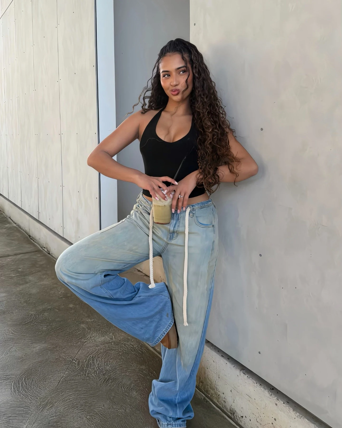 Woman in light-wash drawstring baggy jeans and a built-in bra cup halter top.