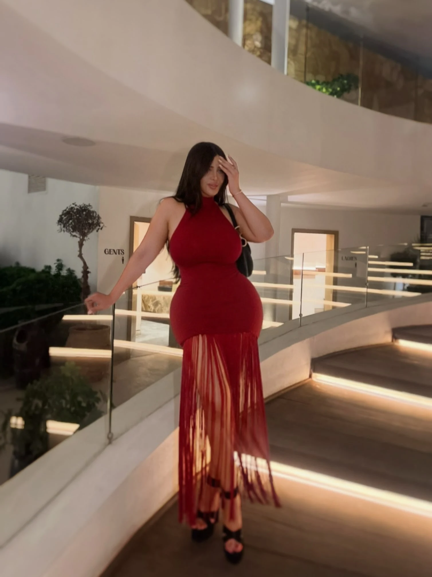 Sleeveless high-neck form-fitting red maxi dress with sheer fringe skirt and black platform heels
